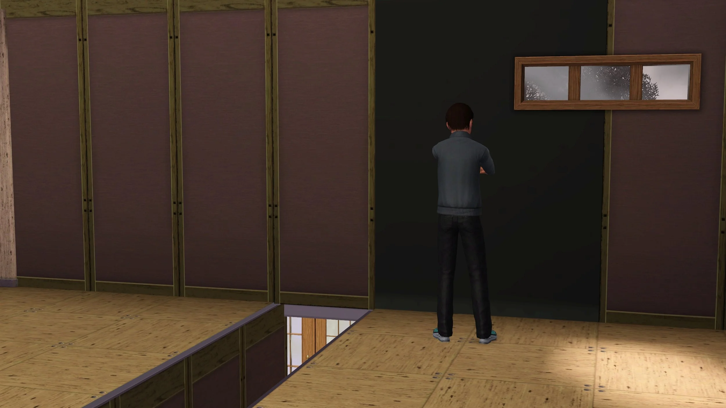 Matthew faces away, focused on a drywall-covered section near a small window of an unfinished room; other walls are wood framed with pink insulation, bare wood subfloor tiles, hole in floor for the staircase (no railing).