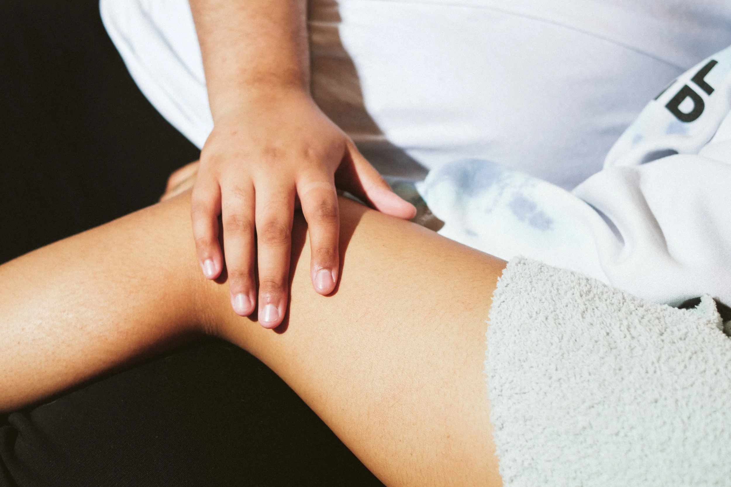 A person receiving a massage on their upper thigh, with a close-up of the hands applying pressure.