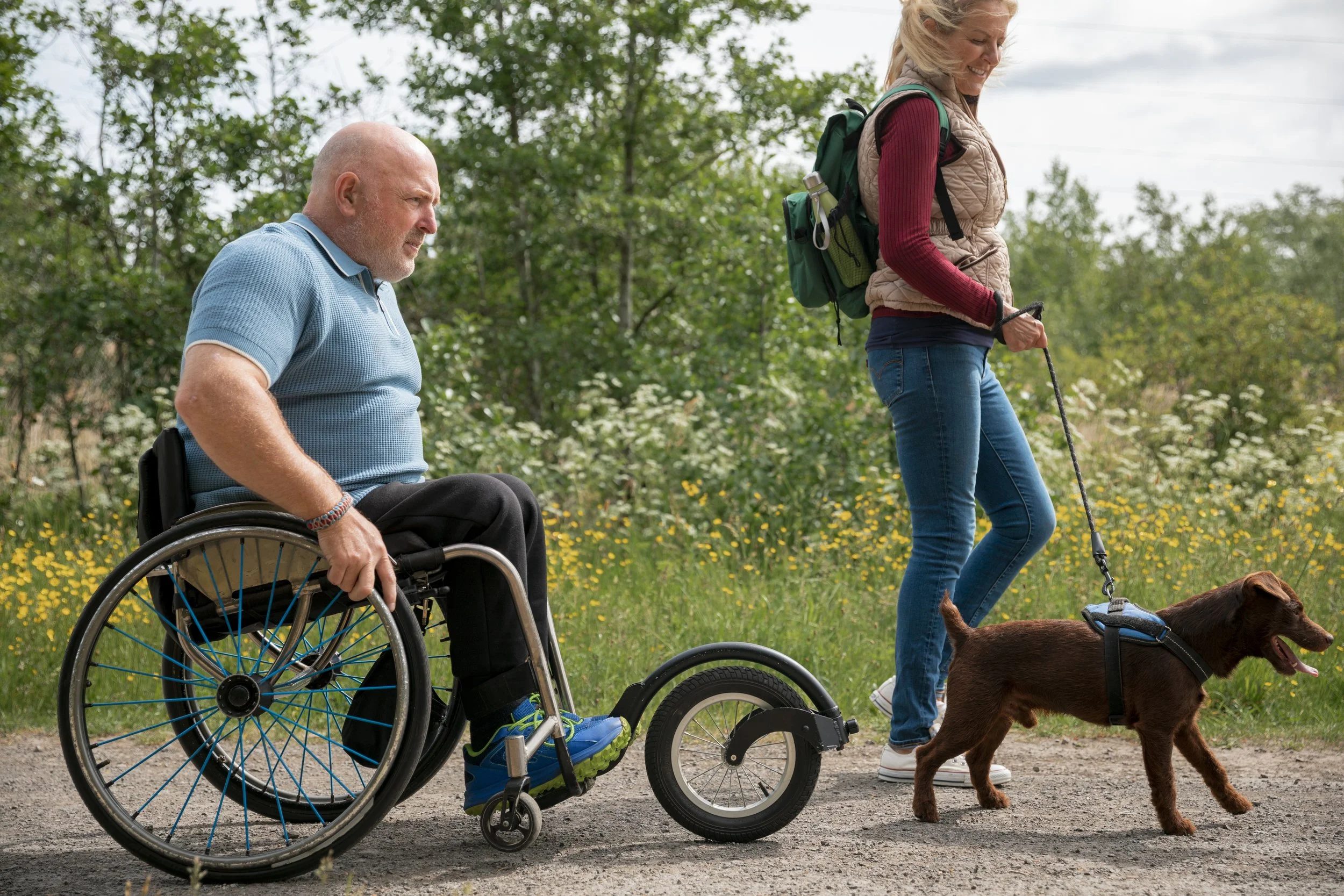 Two women smiling and holding plates of food in a kitchen or food preparation area.