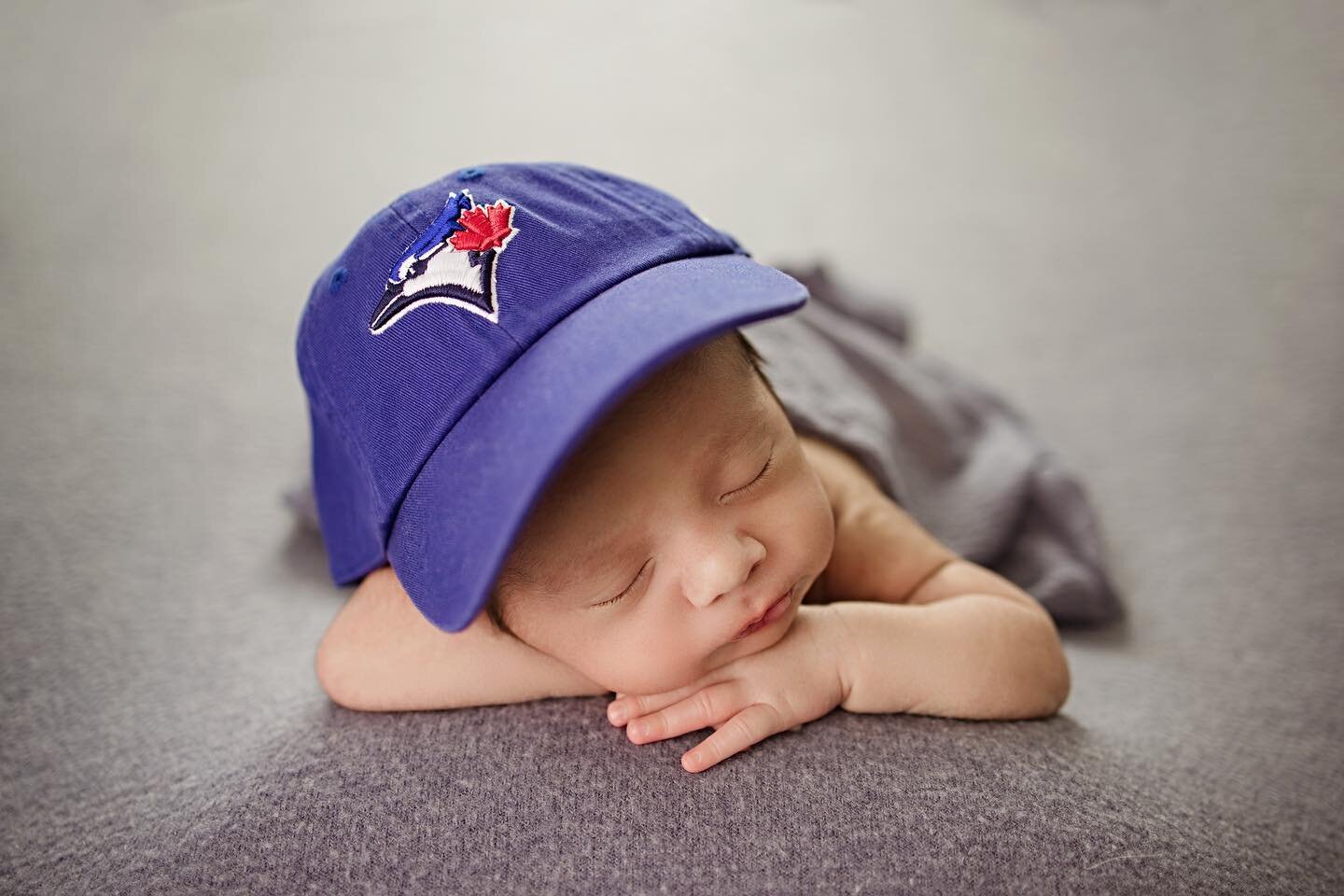 A family moment that spans across generations.

Baby's father wore the same Blue Jay cap in his baby photo, and years later, his boy is now wearing the exact same cap for his baby session. The cap has been passed down from father to son, making it a 