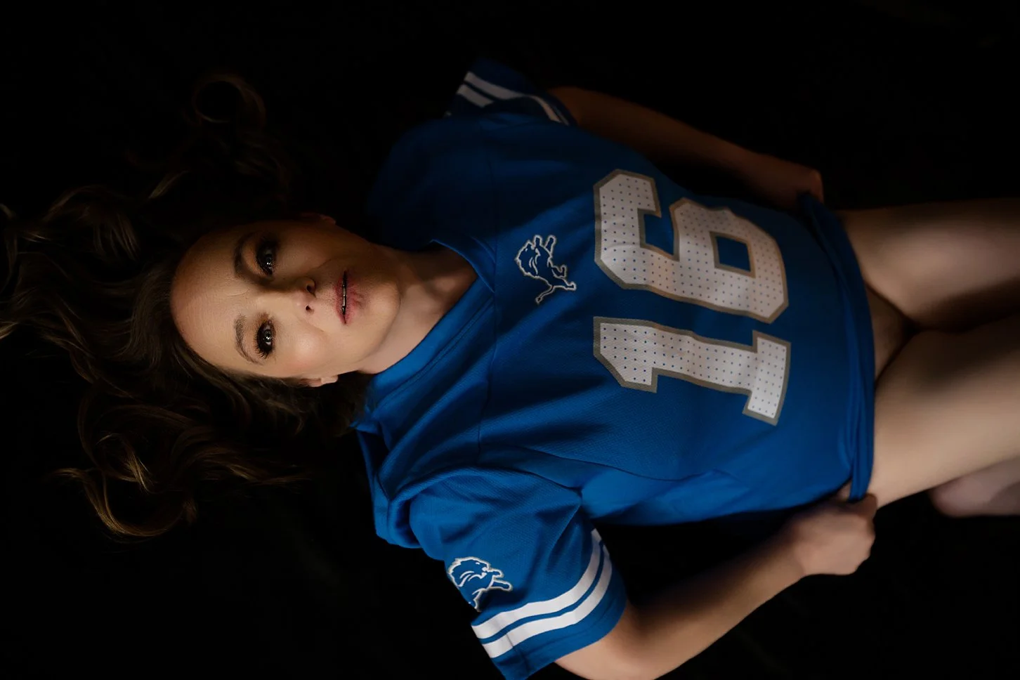 woman laying on bed in blue Lion's jersey
