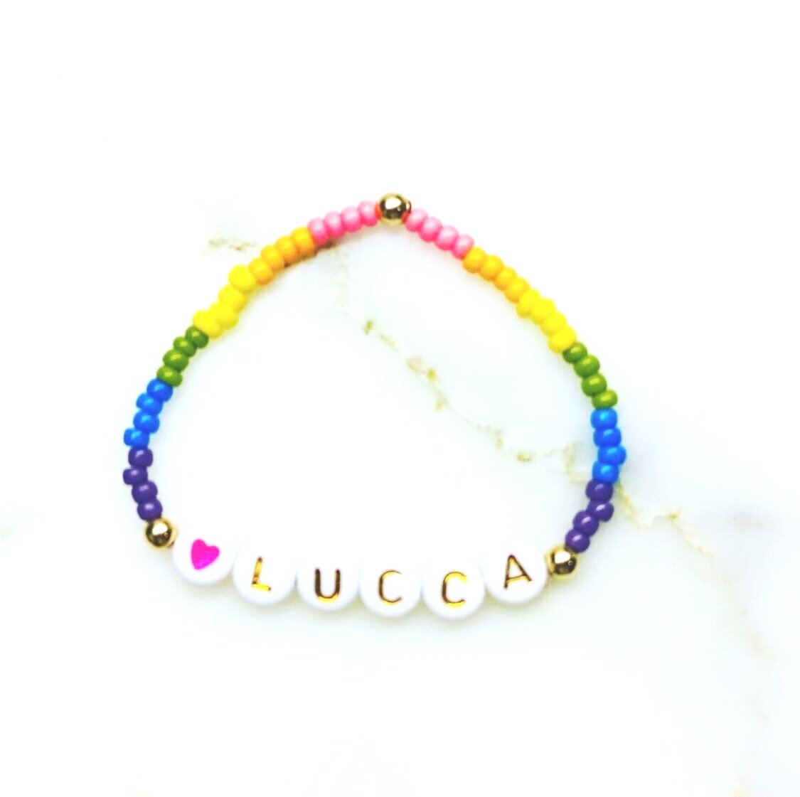 Our Rainbow Sherbert bracelet is made up of customized lettering, and colored beads along with 2 14k gold beads.