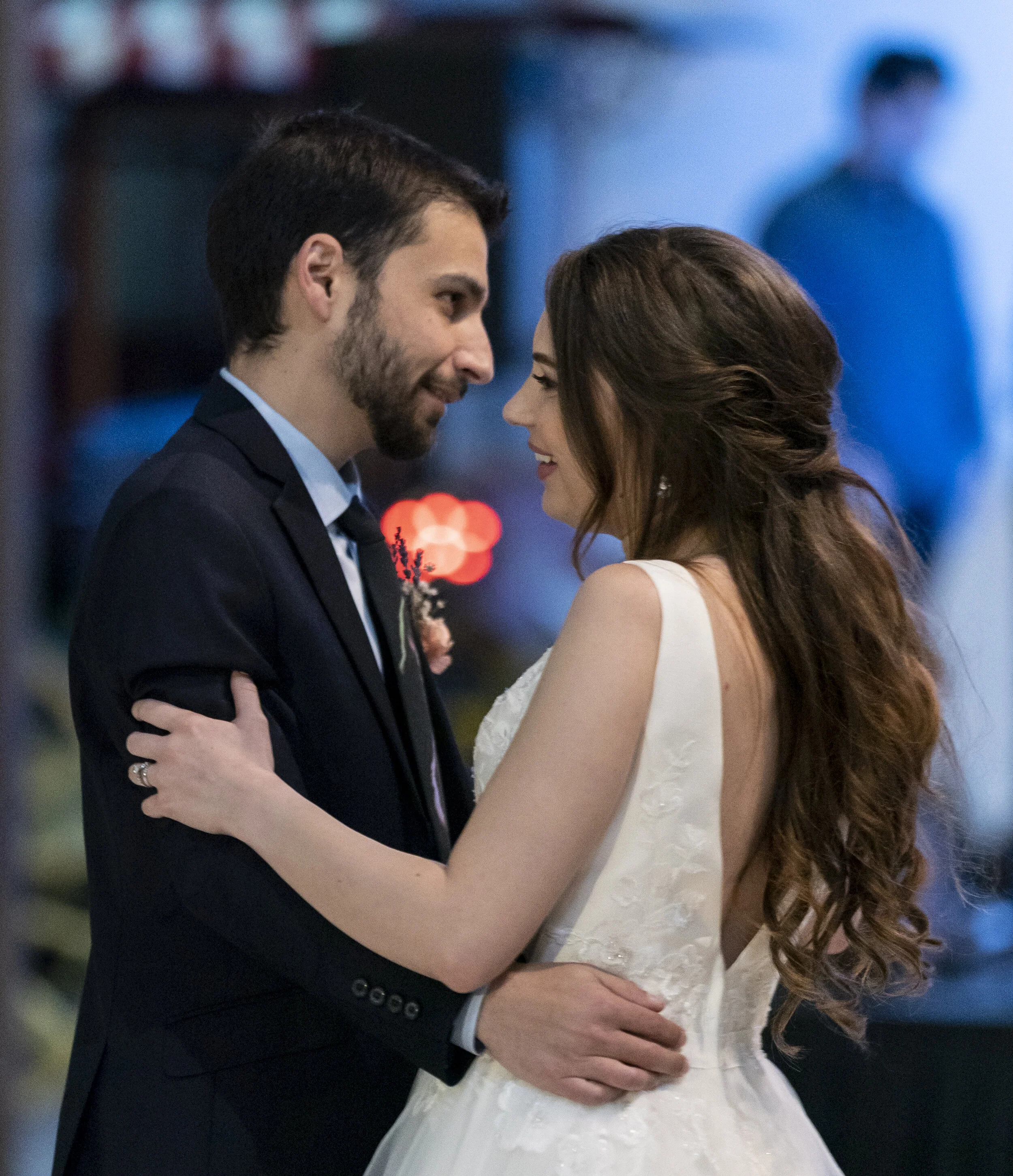 A couple sharing a close moment at their wedding, with the man in a tuxedo and the woman in a white wedding dress, smiling at each other.