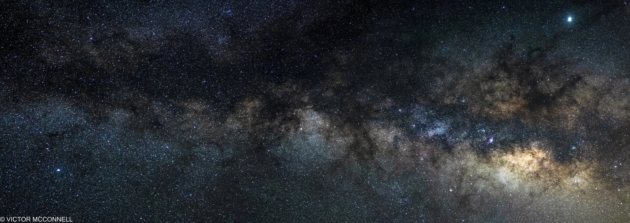 Night sky with a dense field of stars and the Milky Way galaxy visible across the sky.