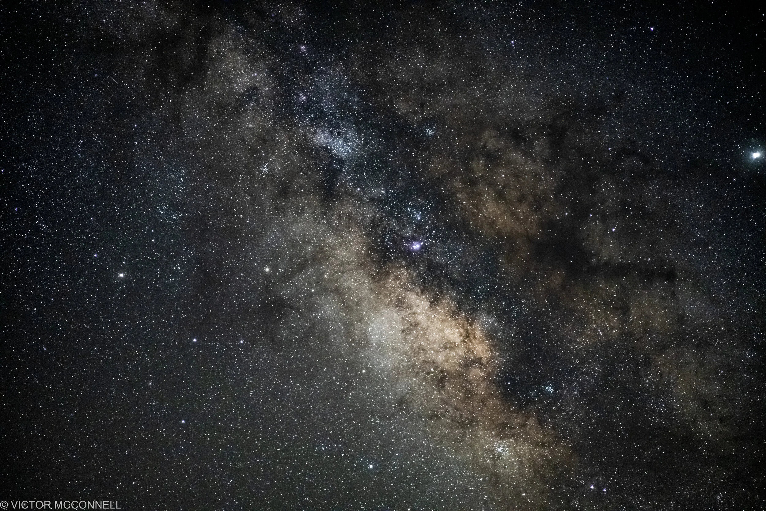 A clear view of the starry night sky with countless stars and a faintly visible Milky Way galaxy.