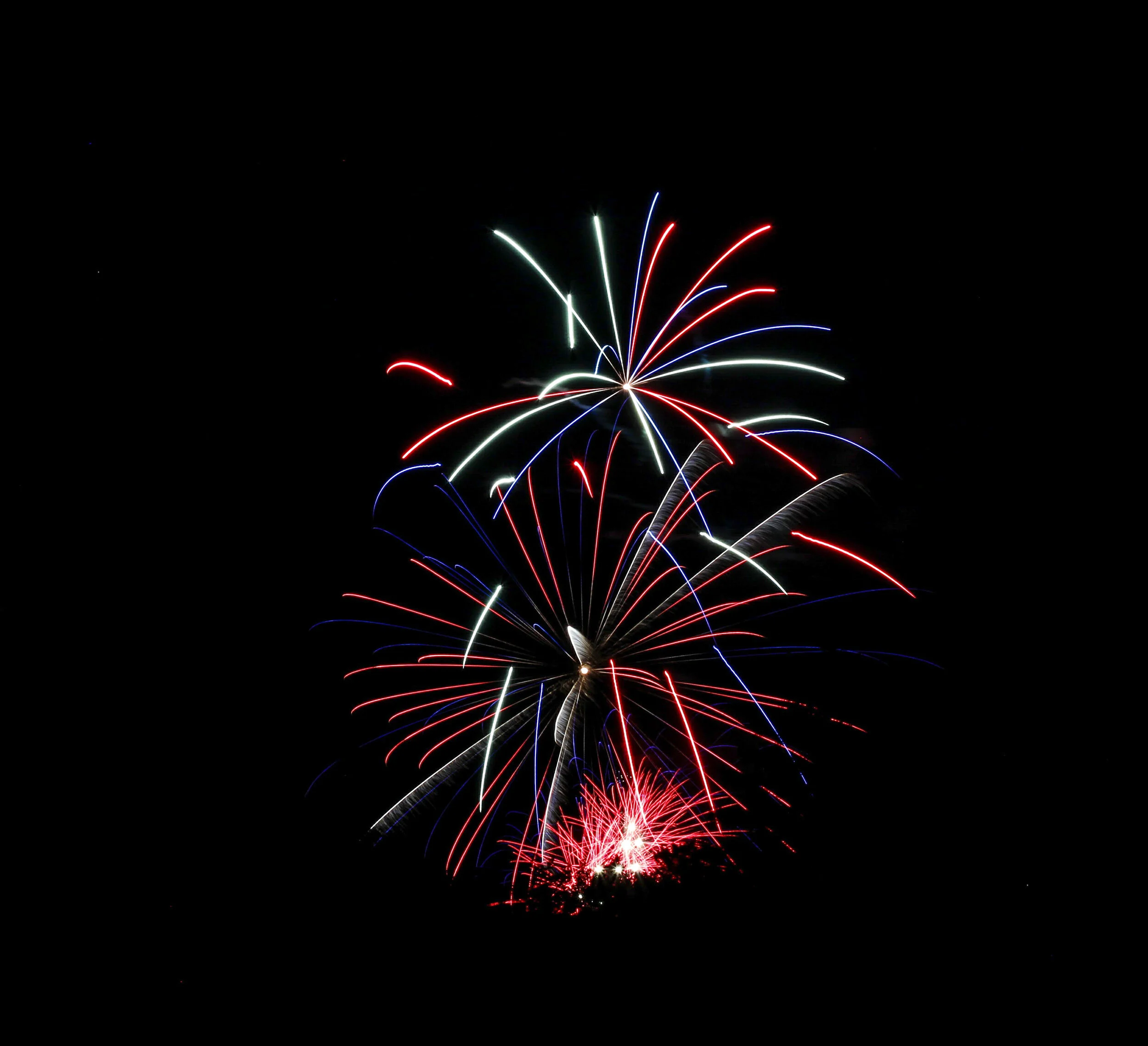 Colorful fireworks lighting up the night sky with trails of red, blue, green, and white sparks.