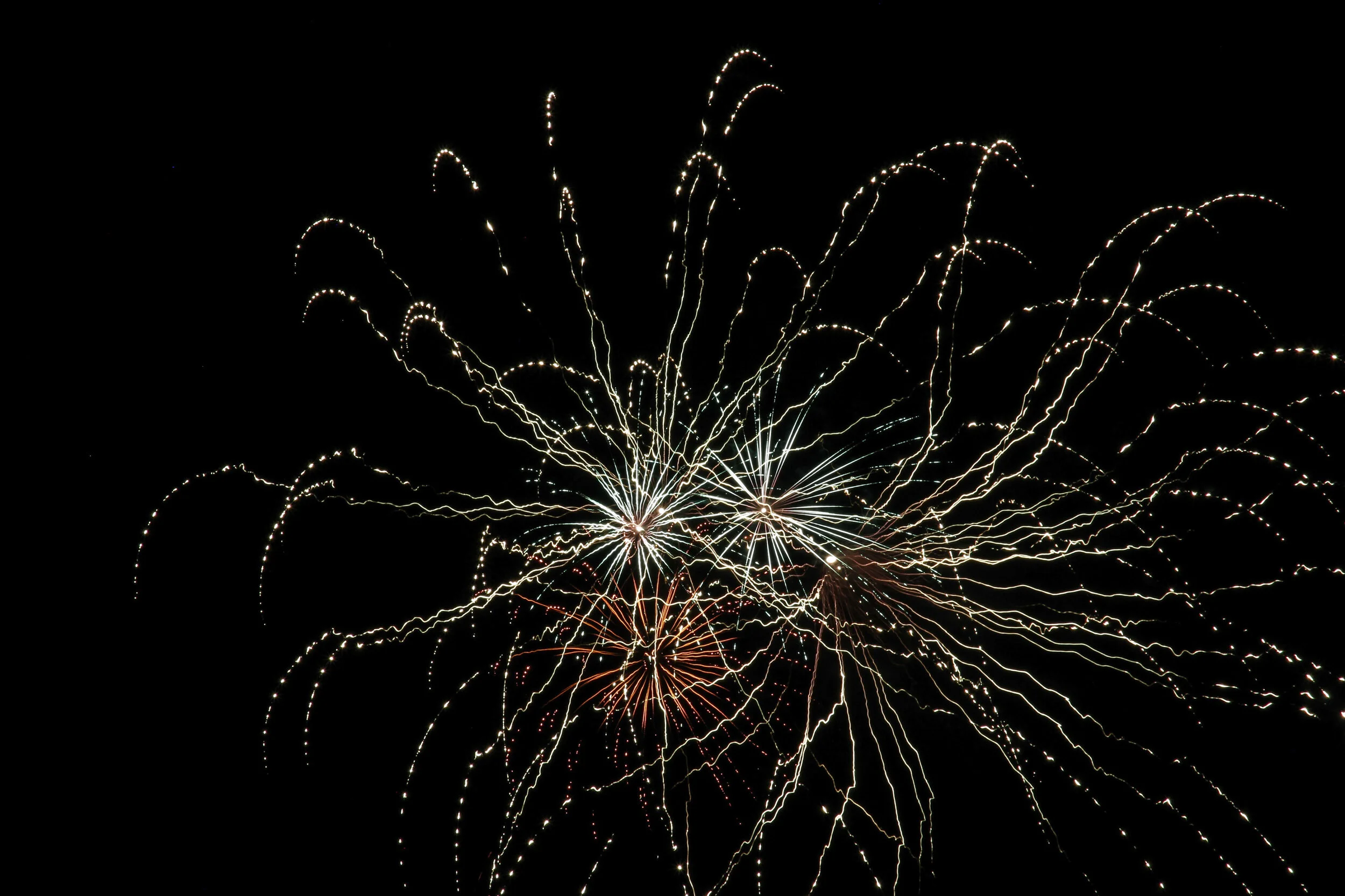 Fireworks exploding in the night sky with bright, colorful streaks and sparks.