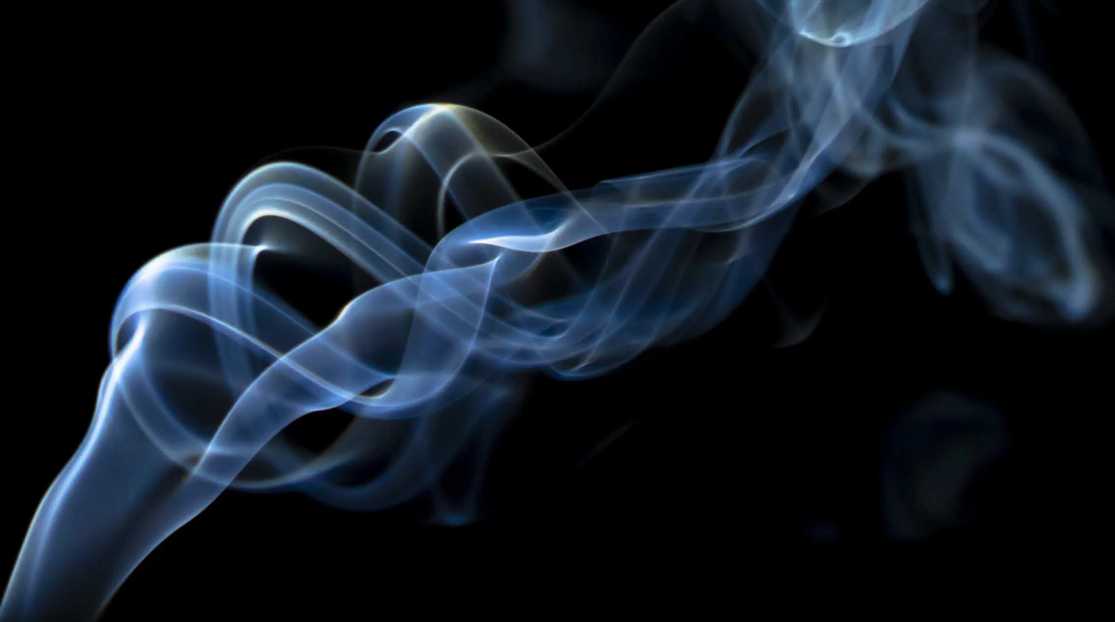 Blue and white smoke wisps twisting against a black background.