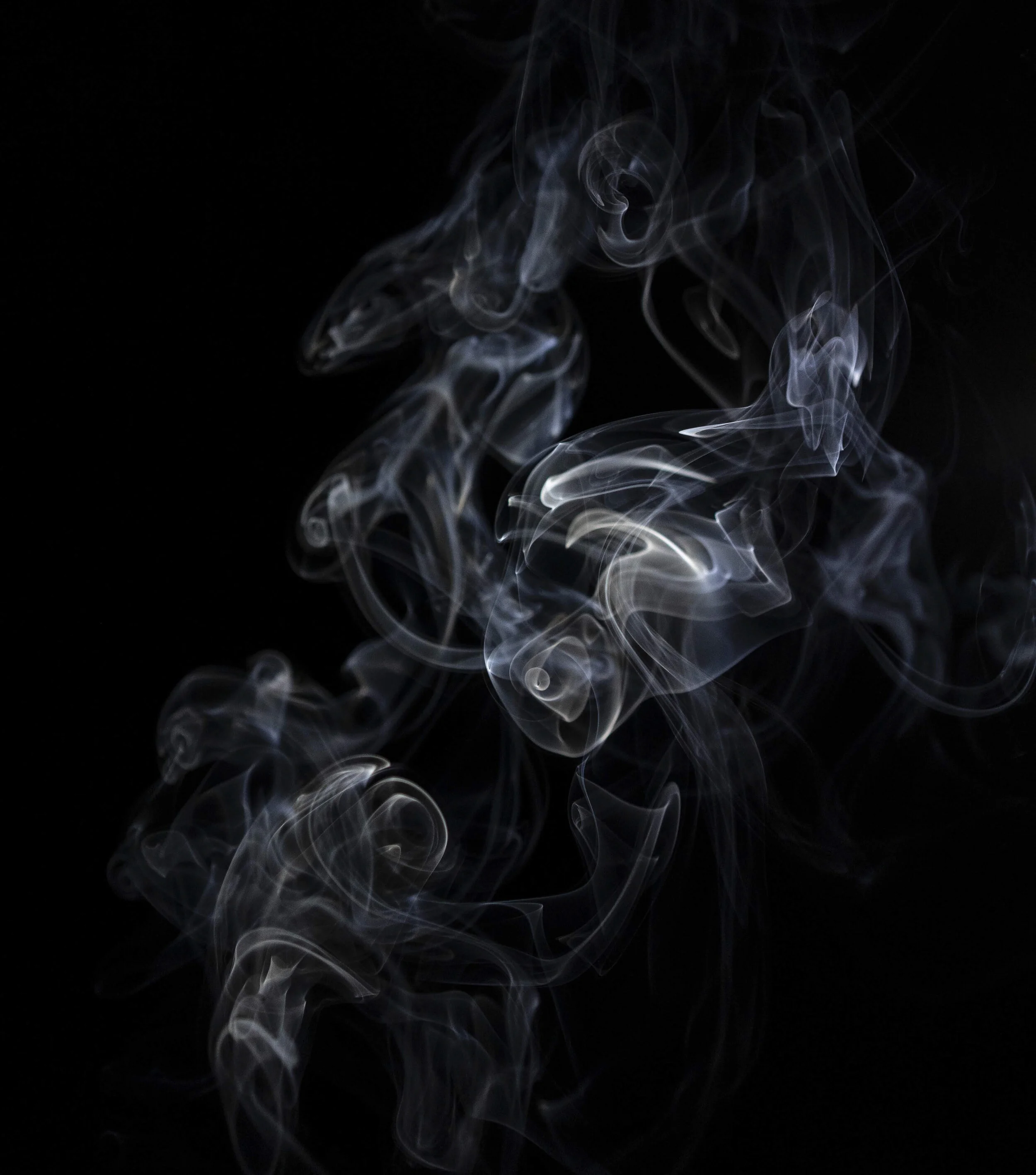 Grayish-white smoke curls and swirls against a solid black background.