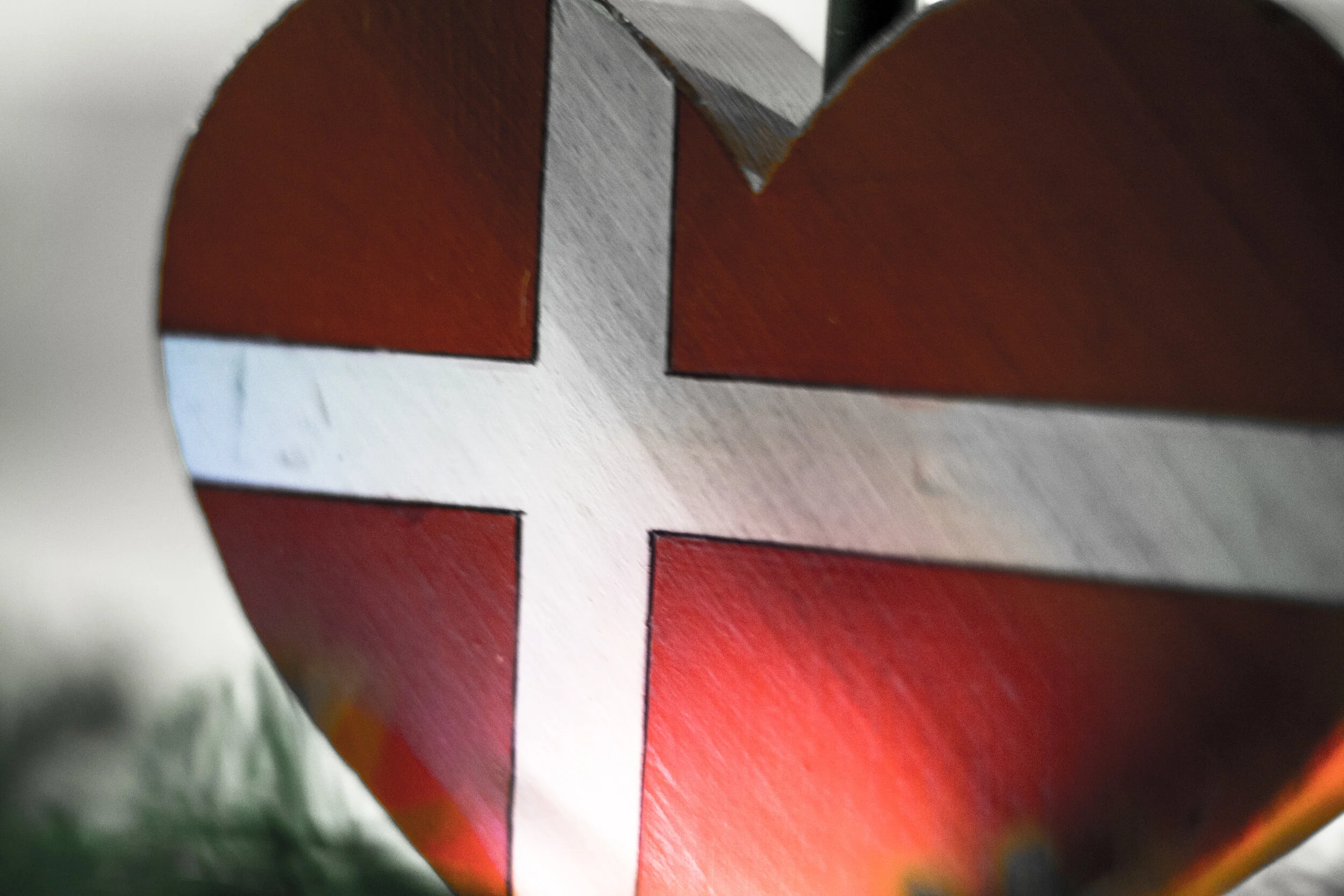 Close-up of a red object with a white cross and black outlines, possibly part of a larger design or sculpture.