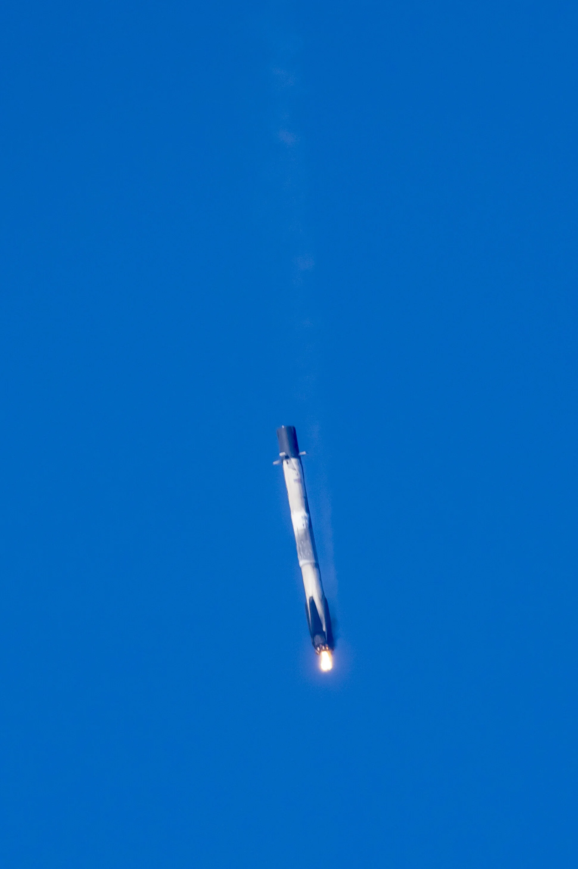 Rocket launching into a clear blue sky, with fire and smoke at the base.