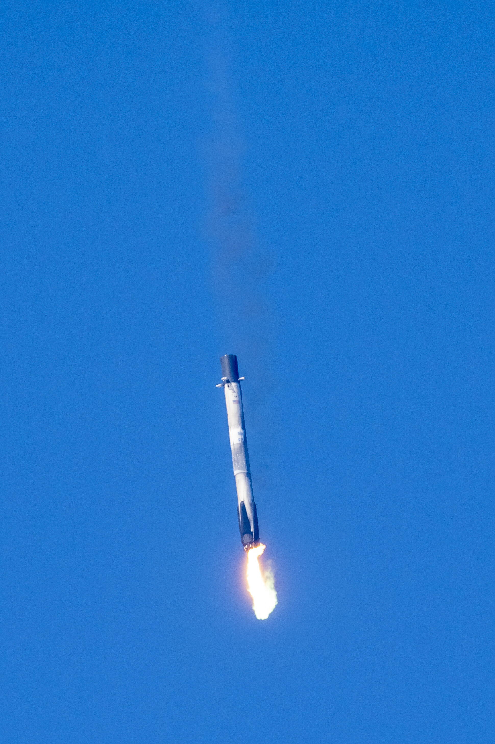 A rocket ship launching into a clear blue sky, with flames and smoke at the base.
