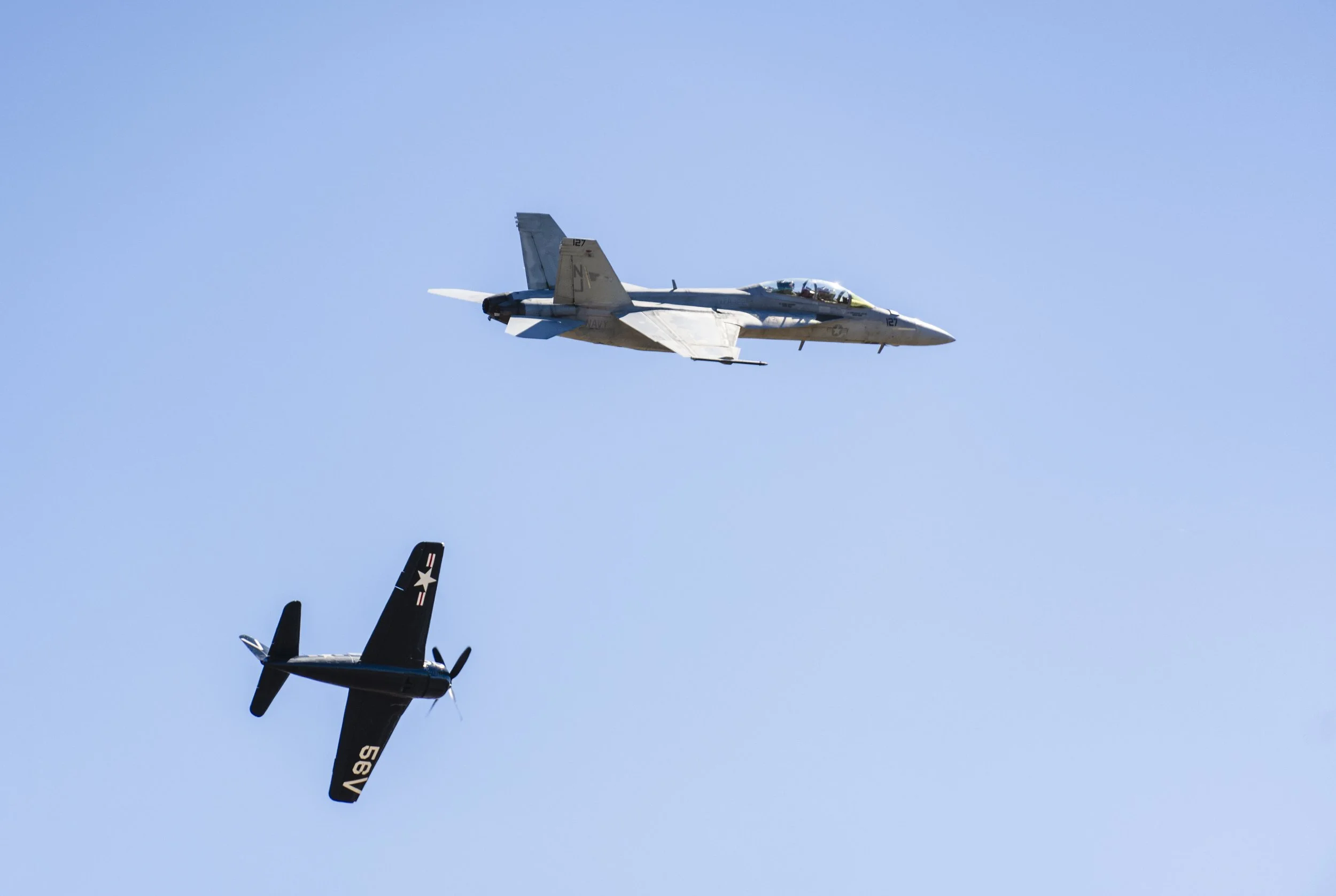 An aircraft flying in the sky alongside a helicopter, with the tail fins of other aircraft visible at the bottom.