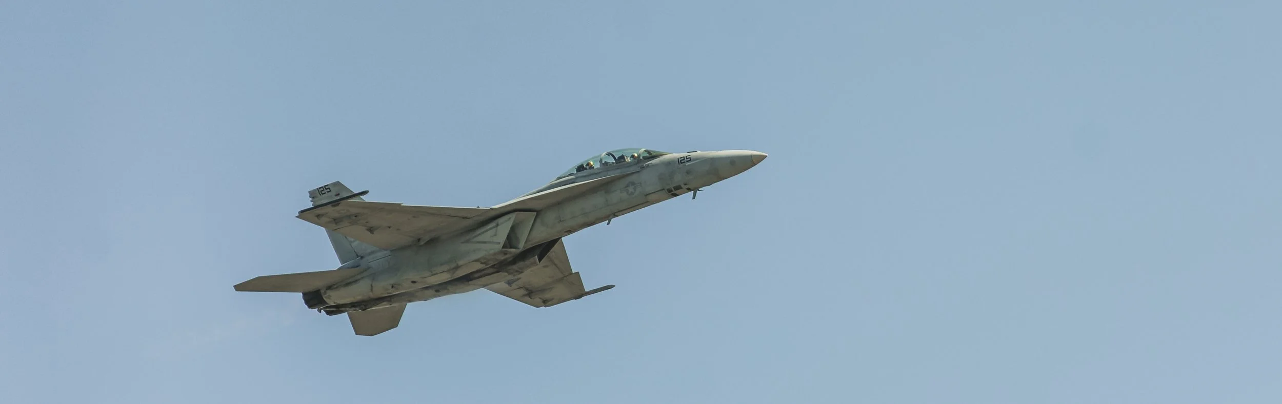 A fighter jet flying in clear blue sky.