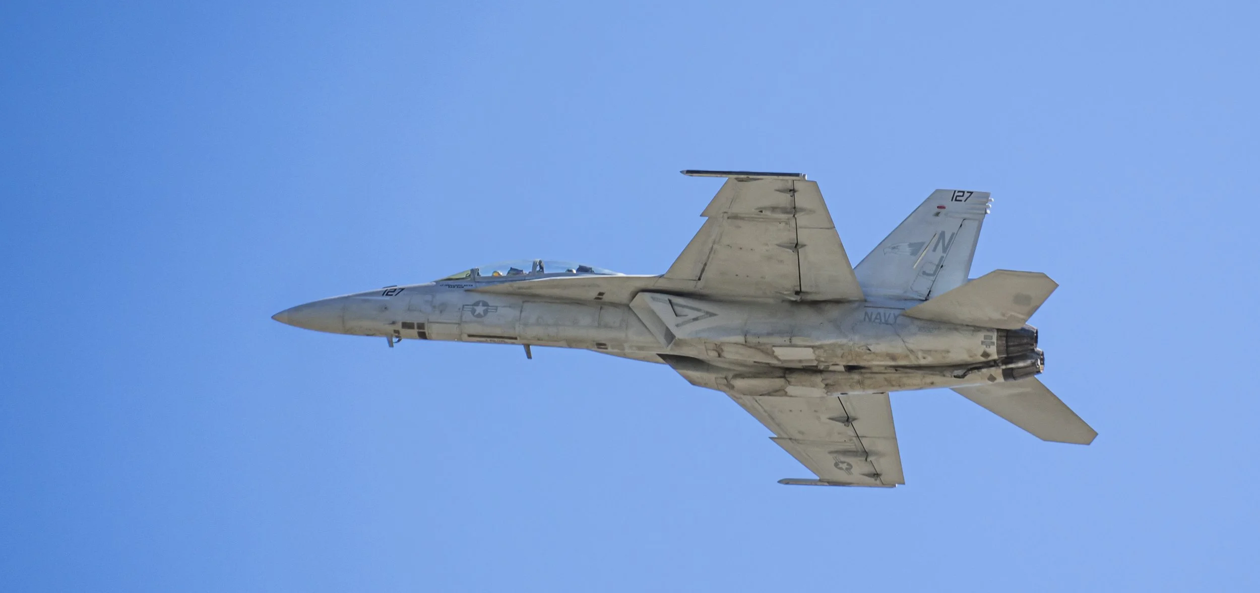 A fighter jet flying in clear blue sky.