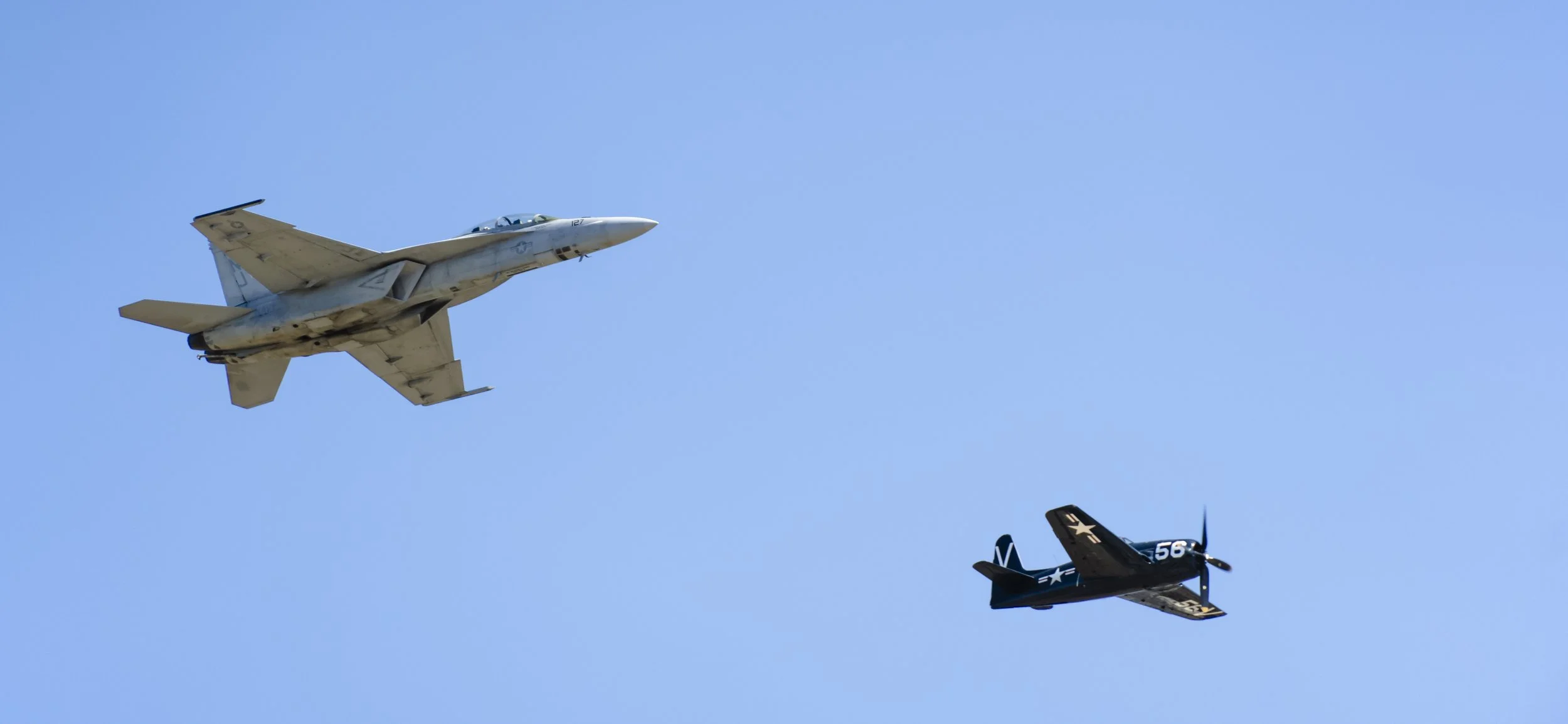 A commercial jet and two small vintage fighter planes flying in clear blue sky.