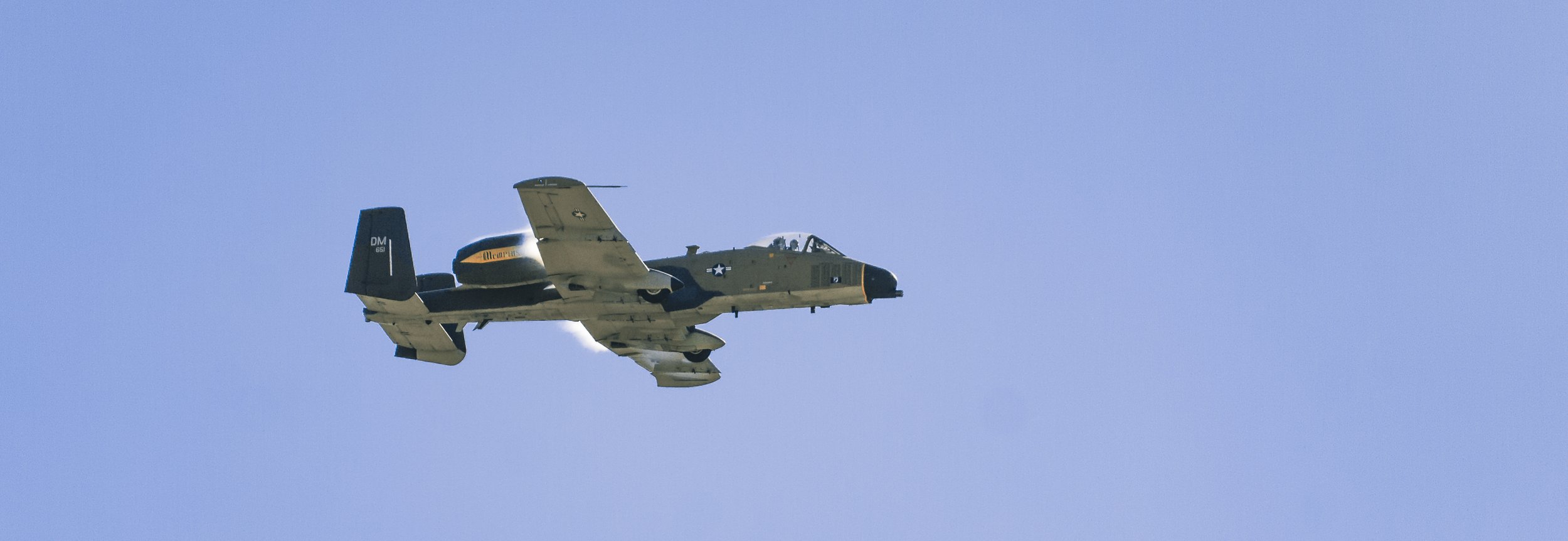A military aircraft flying in a clear blue sky.