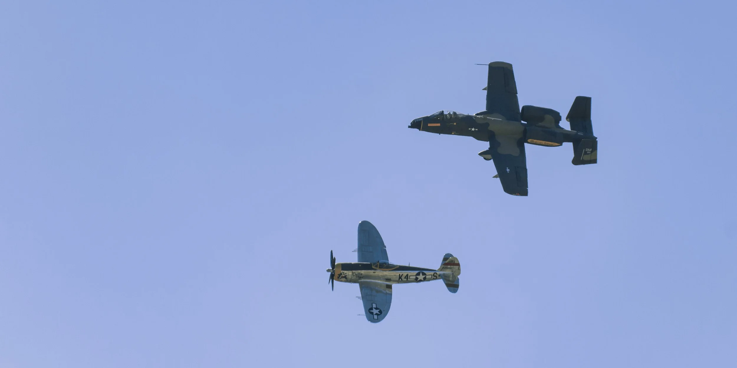 Three vintage aircraft flying in formation against a blue sky.