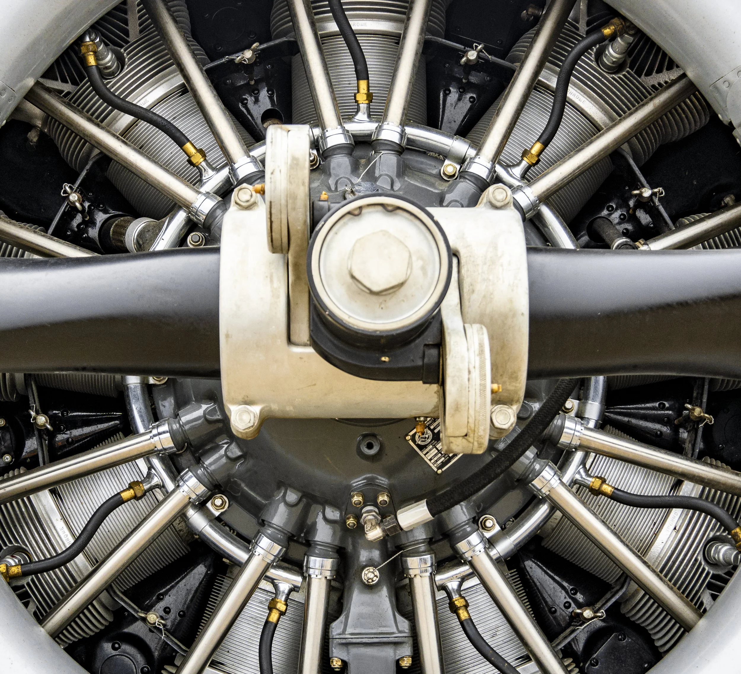 Close-up of a complex aircraft engine with multiple metallic cylinders, pipes, and mechanical components.