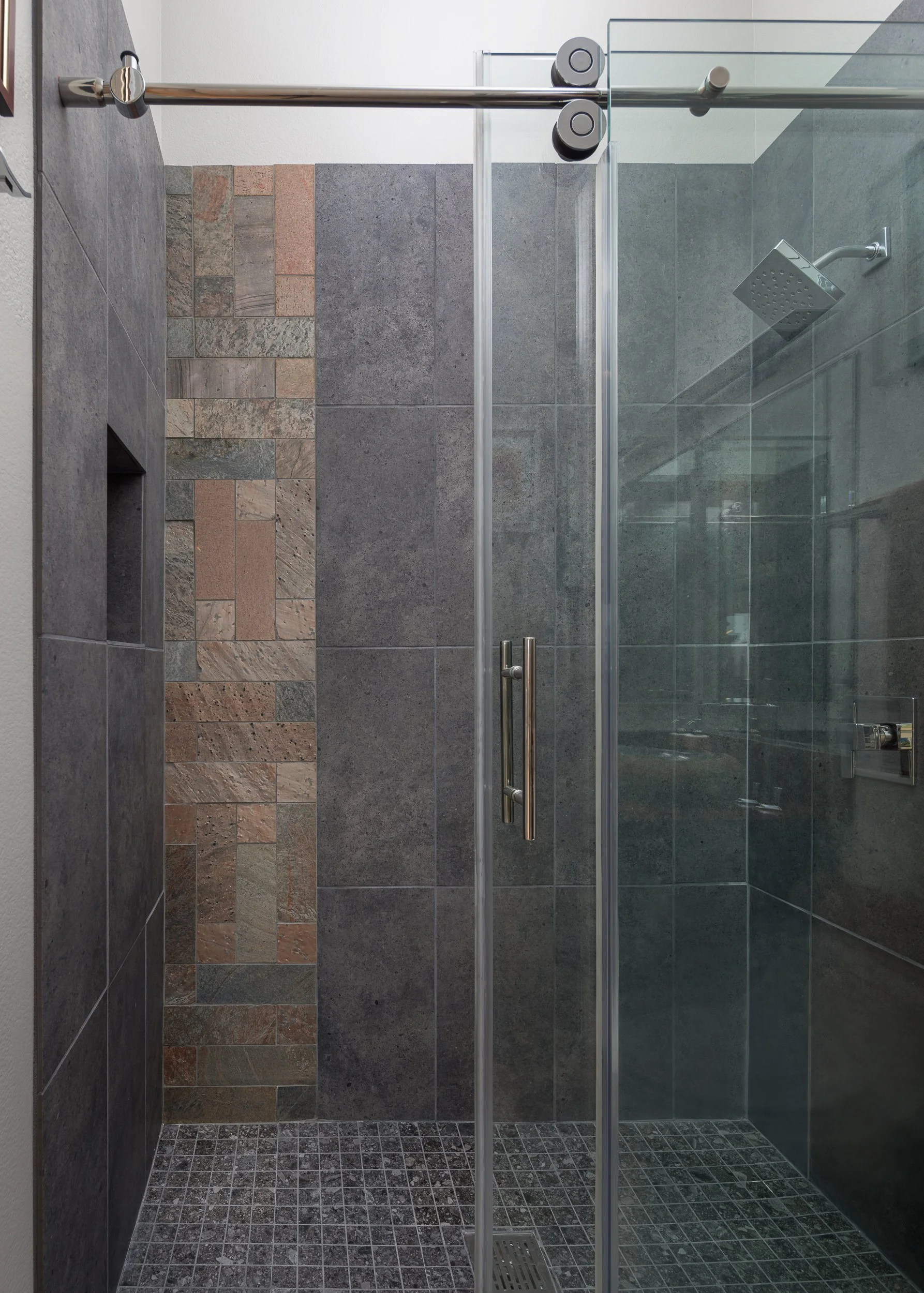Elegant bathroom featuring glass shower enclosure, custom lighting, and dark stone finishes designed by De Atelier Design in Henderson