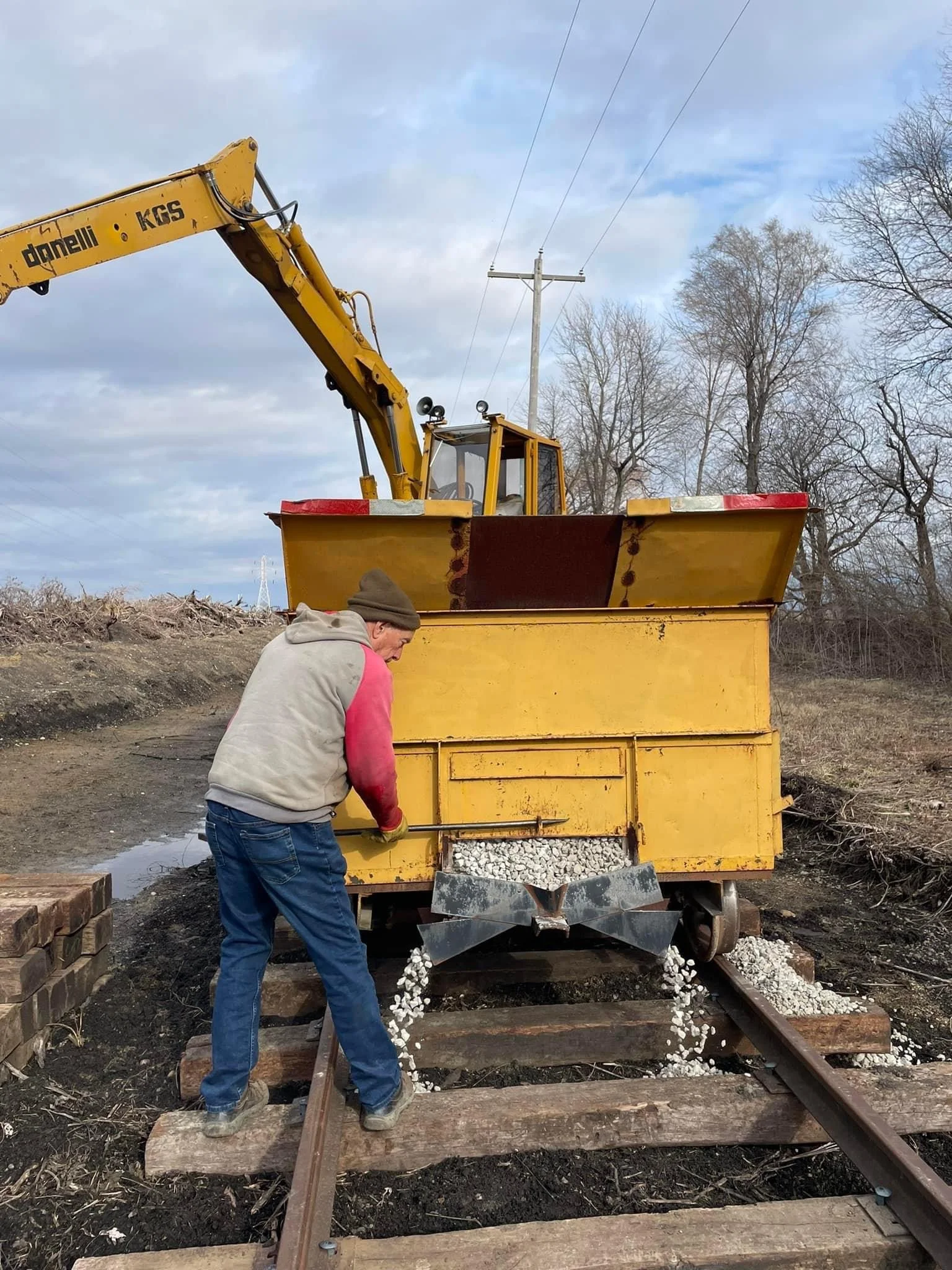  Once the track has been skeletonized, the next step is placing ballast, which are the rocks in the track. Volunteers are using a cart with chutes to place this ballast that has been nicknamed "the rock box." 