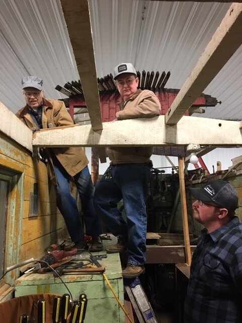 Several volunteers working on the CP snowplow on a cold winter day inside the new heated wood car shop.