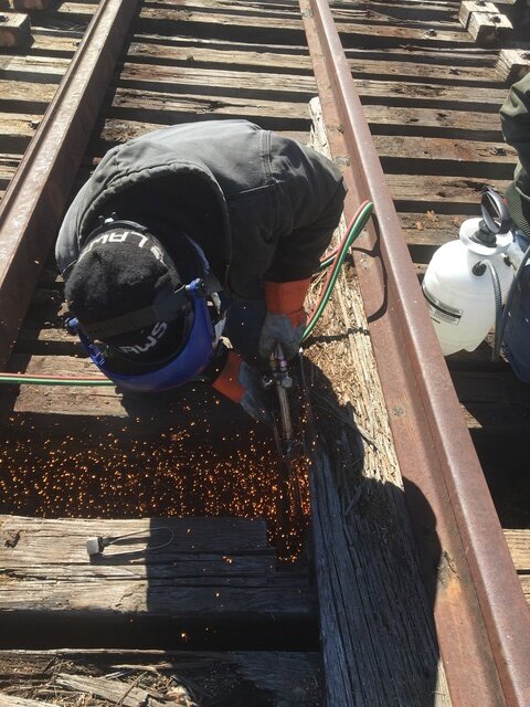 Another volunteer uses a cutting torch to remove bolts holding the deck together.