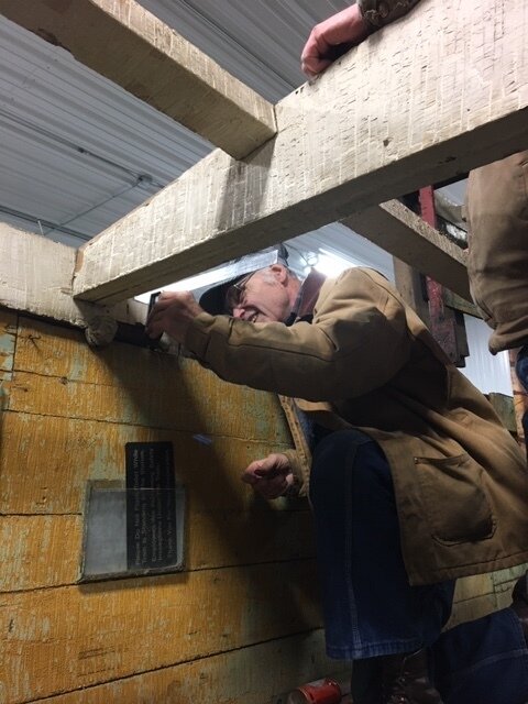 Volunteer checking and measuring depth of cut for replacement wood pieces being installed.