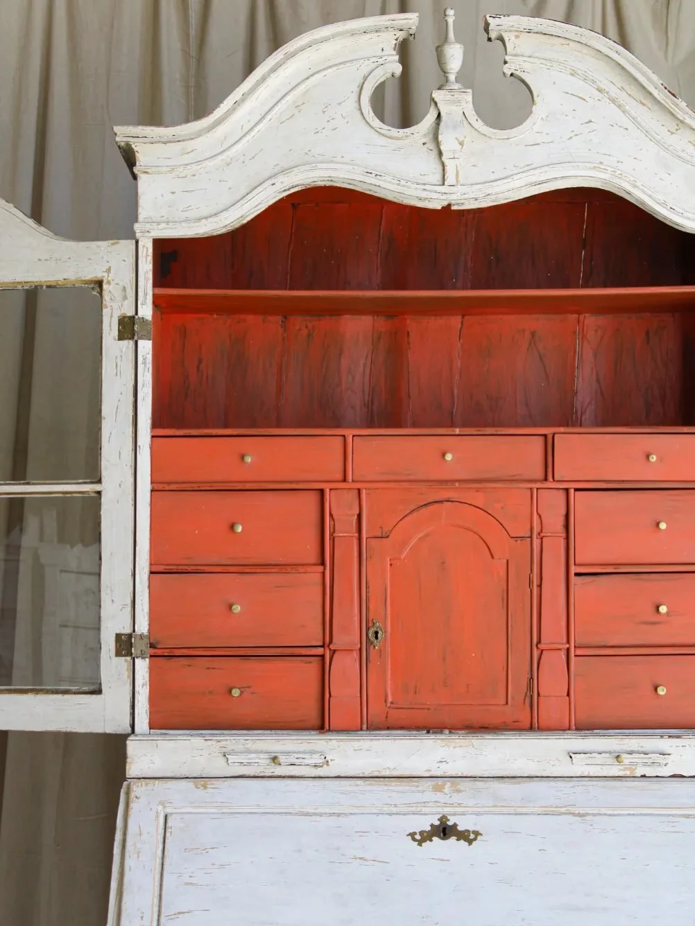 The Antique Arthur Secretary showcases exquisite Swedish craftsmanship with ornate detailing atop its attached hutch. 

Inside, the burnt orange interior houses numerous small compartments, perfect for organized storage. Elegant gold-toned hardware c