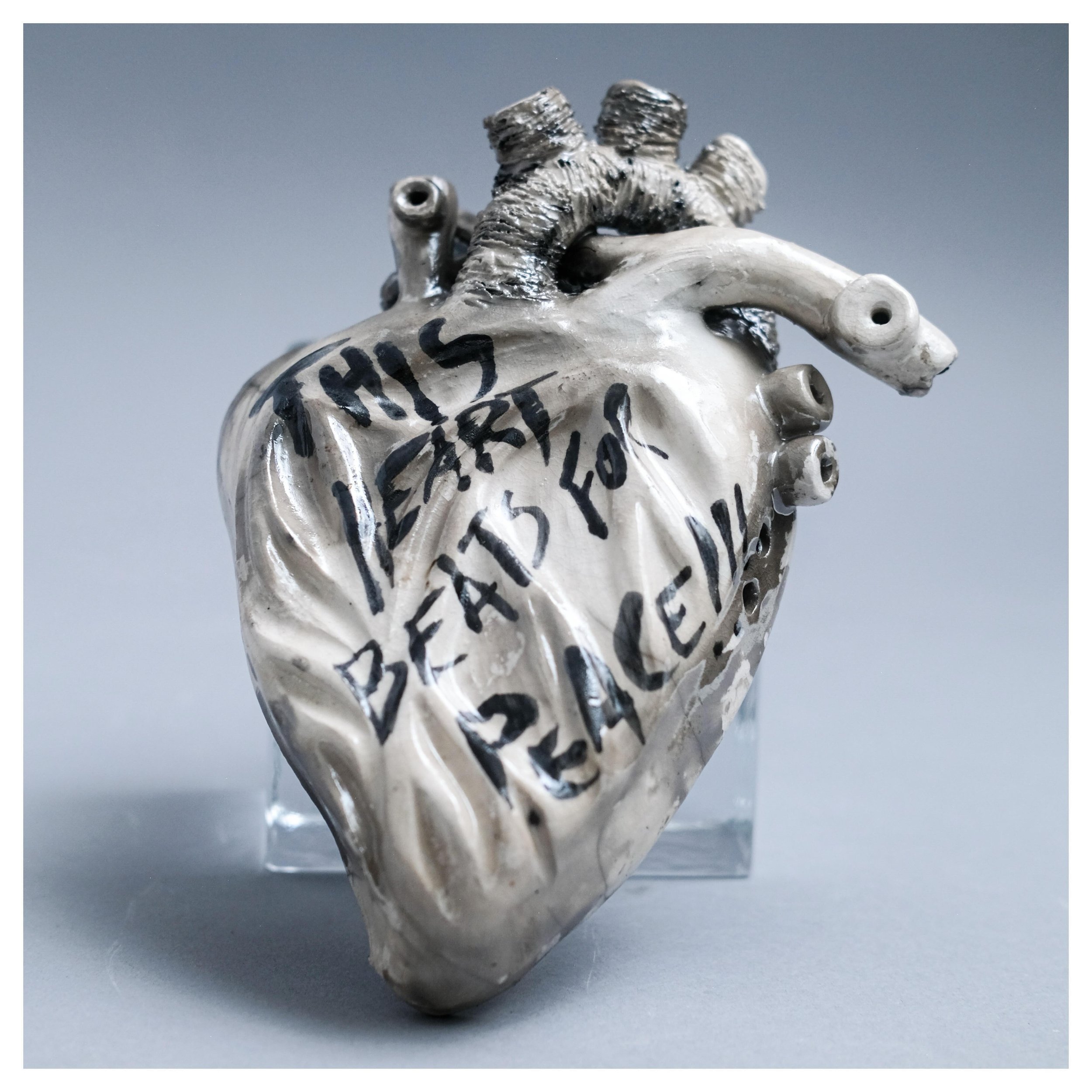 In a time marked by conflict and division, where voices are silenced and ideologies clash, this heart stands as a beacon for empathy.  Raku-fired the carbon smoke emphasizes the cracks, to distress the surface of the heart marked with hand painted wo