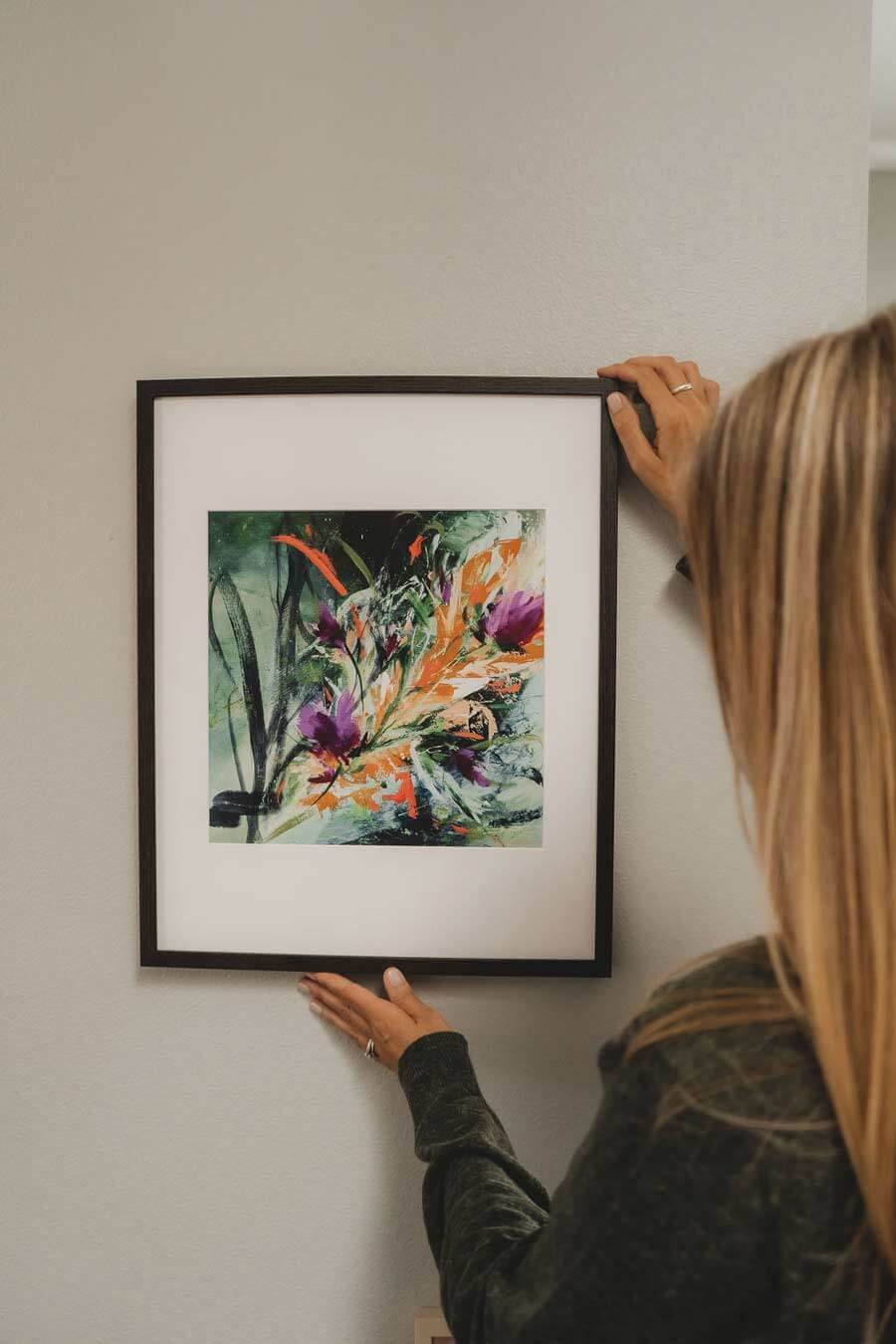 Framed floral art being hung on a wall