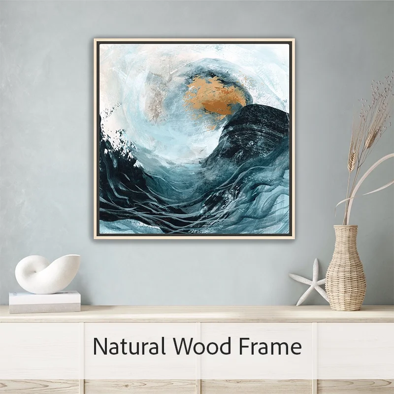 Modern ocean canvas art print featuring a crashing wave in layered blue and coastal tones with a natural wood floater frame on a wall on wall