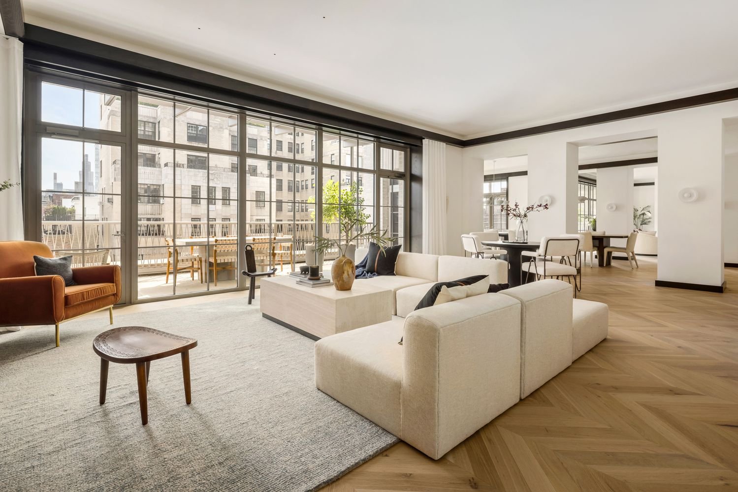 Living room with expansive terrace views, painted in soft tones with black ceiling detail and natural wood floors