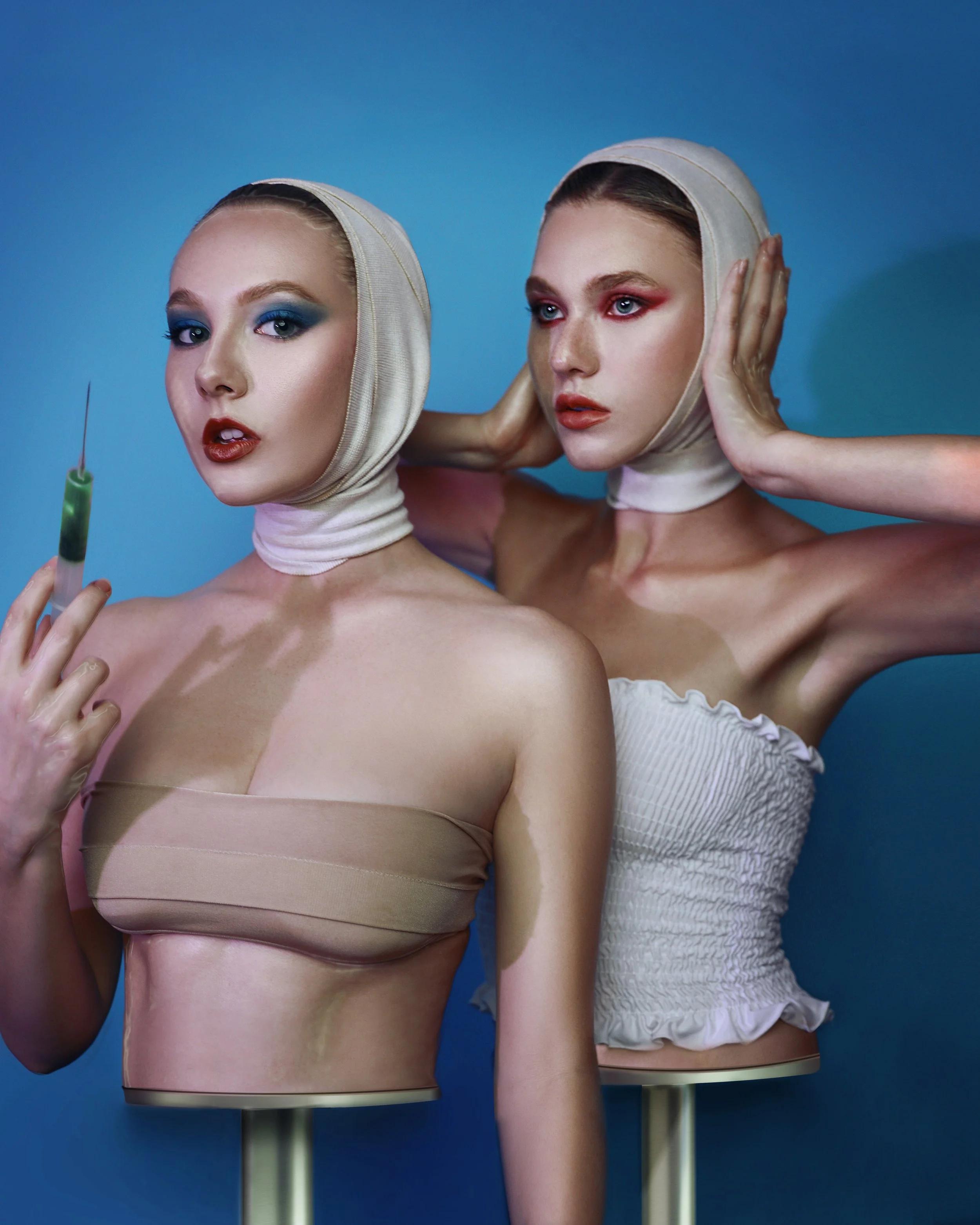 Twin editorial beauty portrait, bandage-wrap headpieces and a syringe prop, dramatic red and blue makeup — KEN X KEEN Orlando