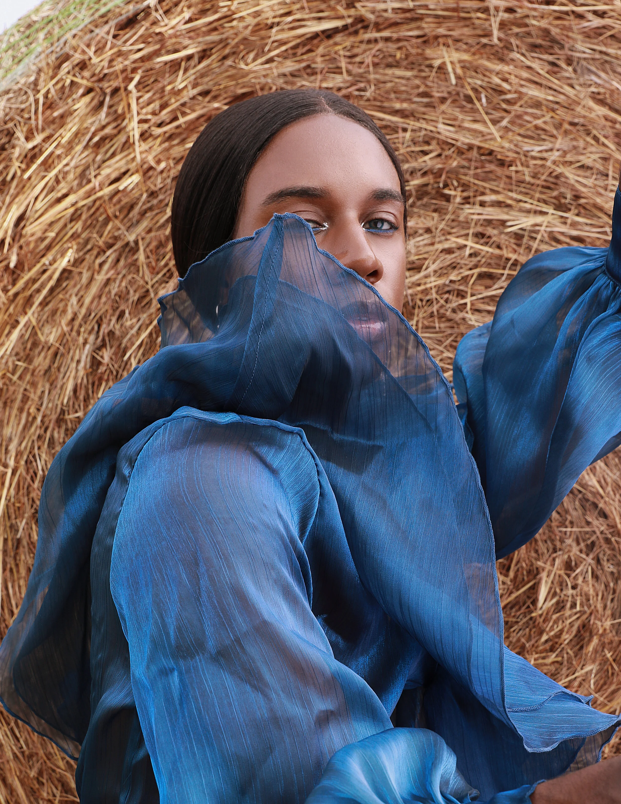 Model in all-blue high-fashion styling in front of round hay bales — editorial concept portrait, KEN X KEEN Orlando