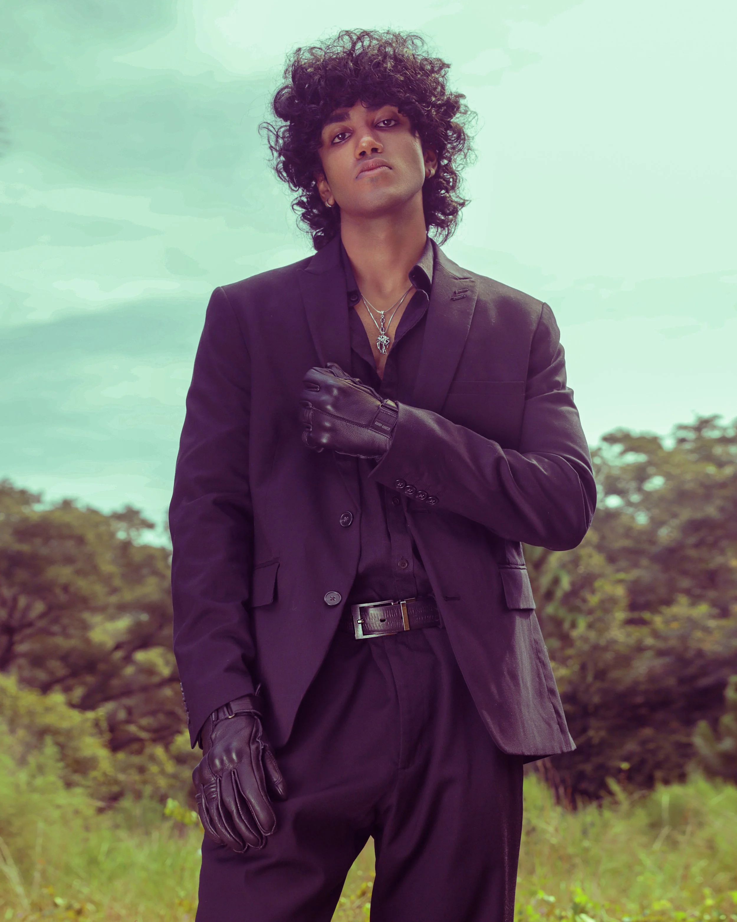 Model in an all-black suit against greenery, long hair — men's editorial ad style, KEN X KEEN Orlando