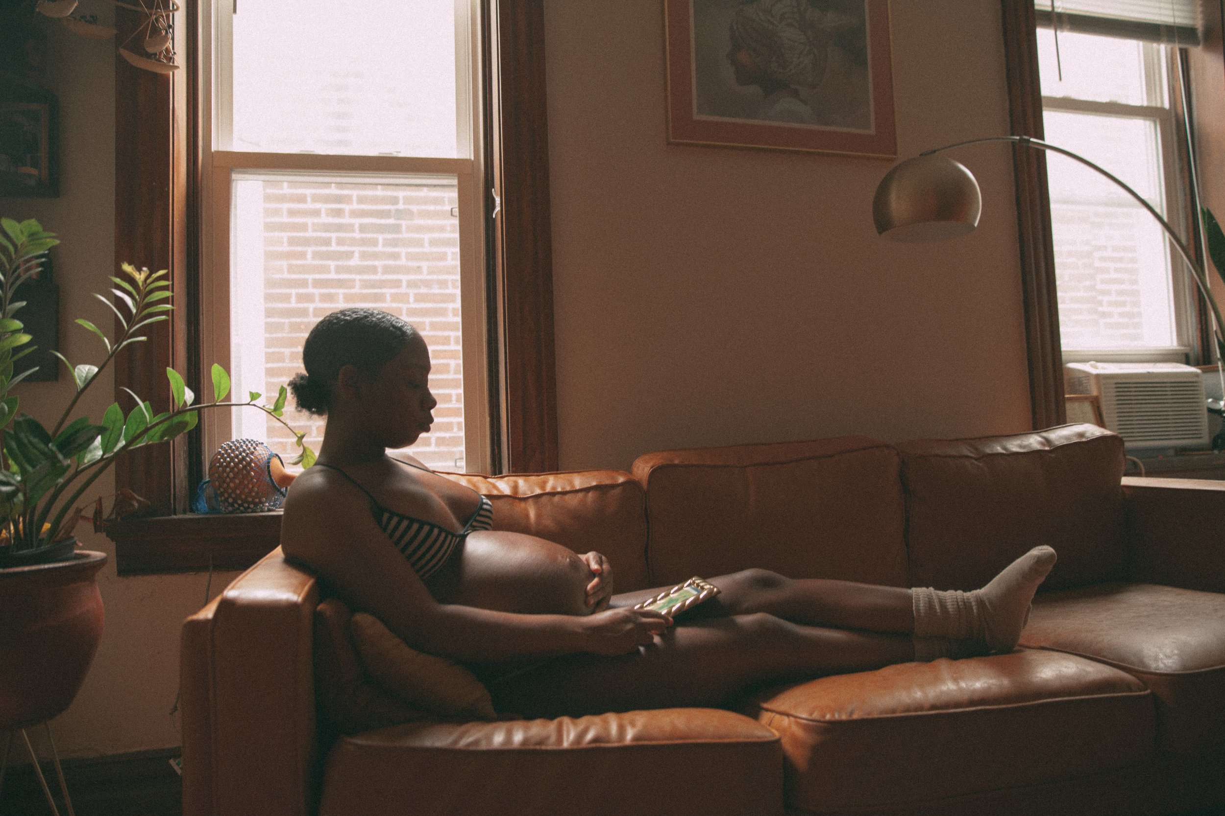 Jamaica sits in with her baby in one hand, with a picture of her Mother in the other. 