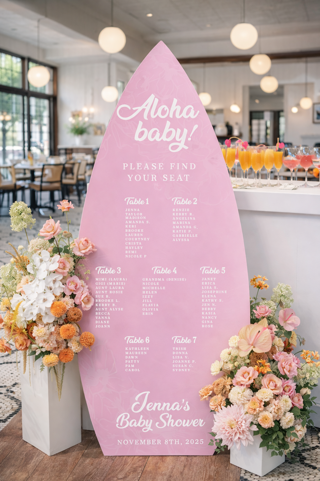 Pink teardrop-shaped seating chart for Jenna's baby shower, November 8th, 2025, with floral arrangements on either side and drinks in the background.