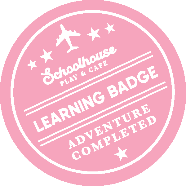 Pink circular badge with white text and icons, indicating a completed adventure badge from Schoolhouse Play & Cafe for learning.