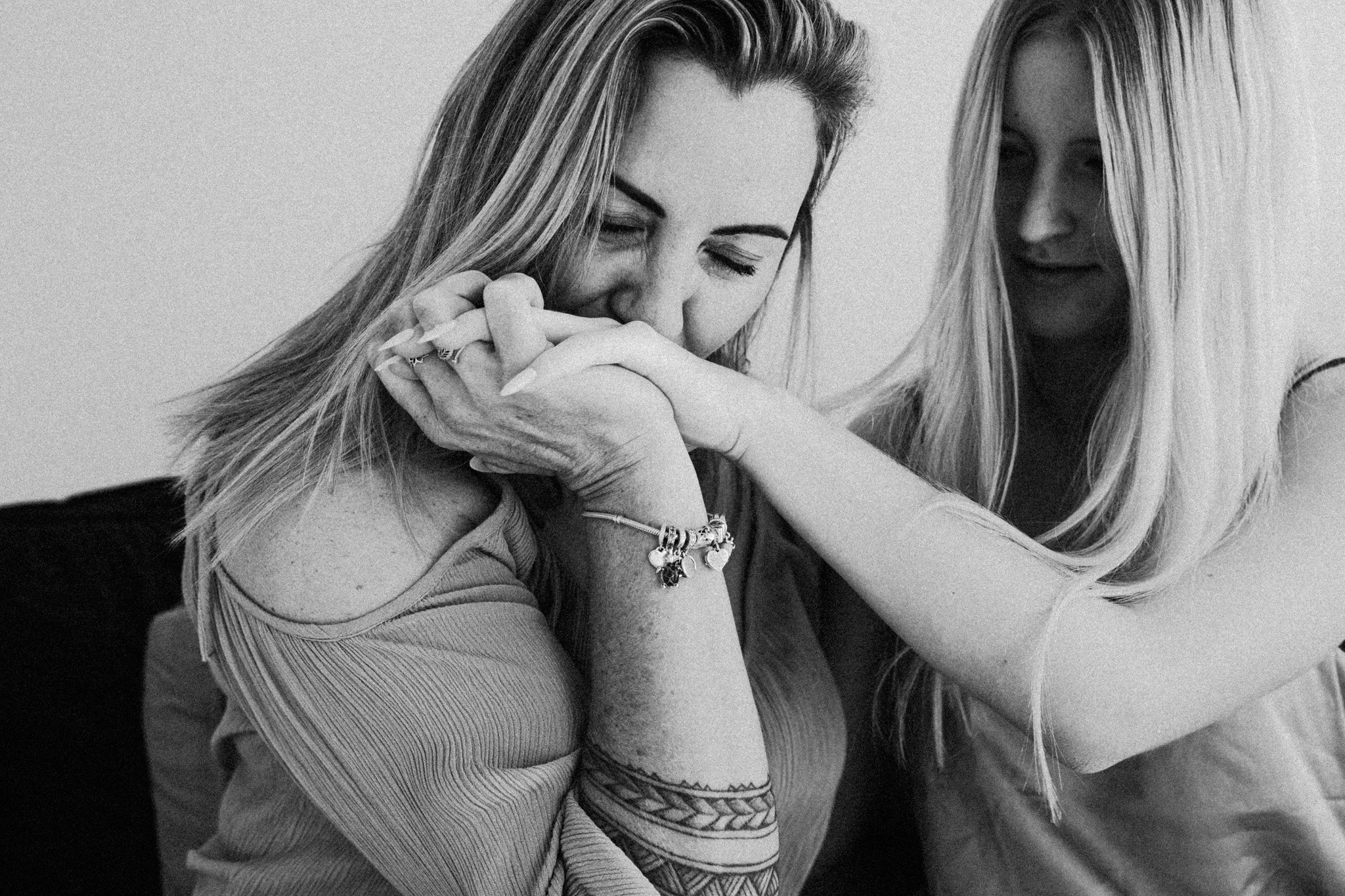 a mother gently kisses the back of her teenage daughters hand.