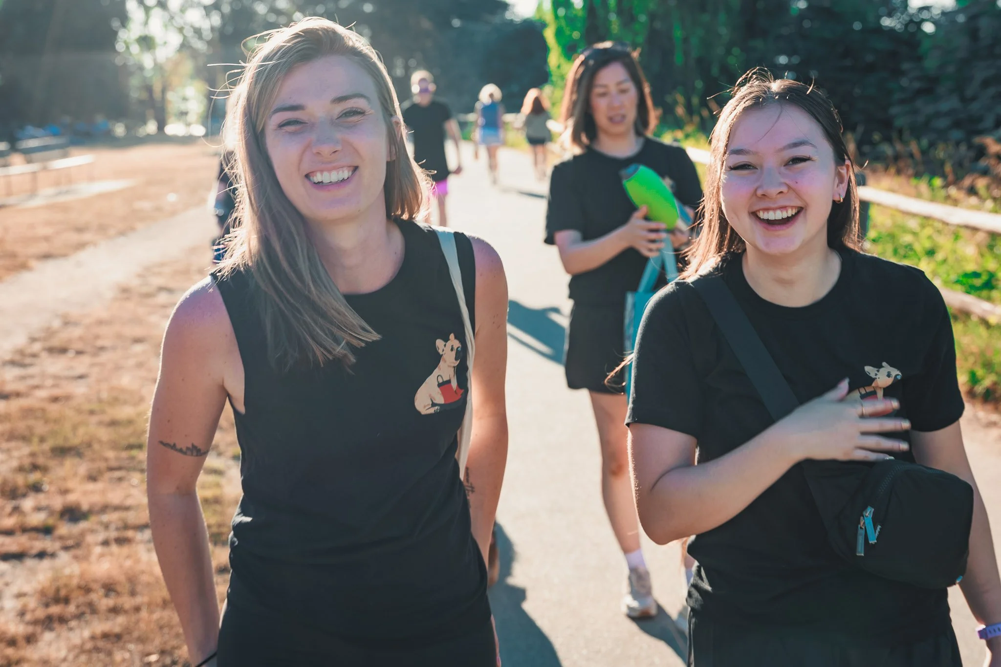 Kris and Dana, two Raintown dog trainers, smile as they walk together on sunny Kitsilano Beach in Vancouver.