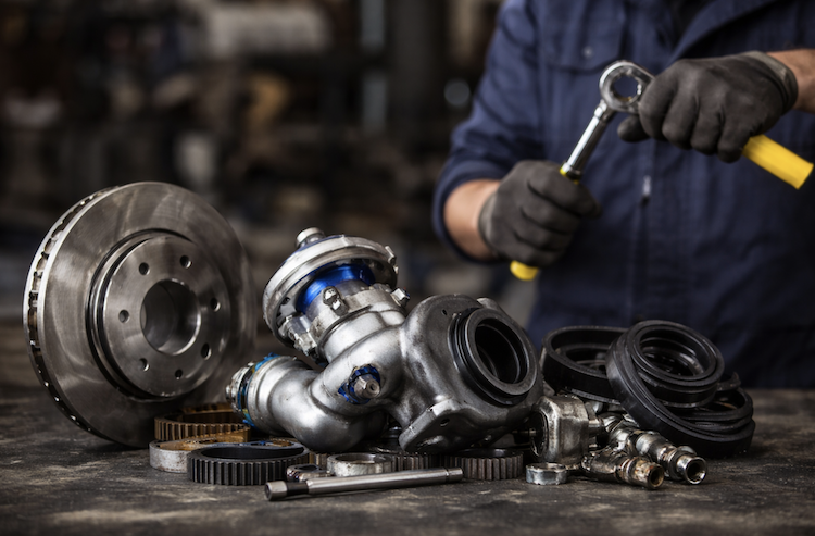 Auto parts on workbench and mechanic installing them