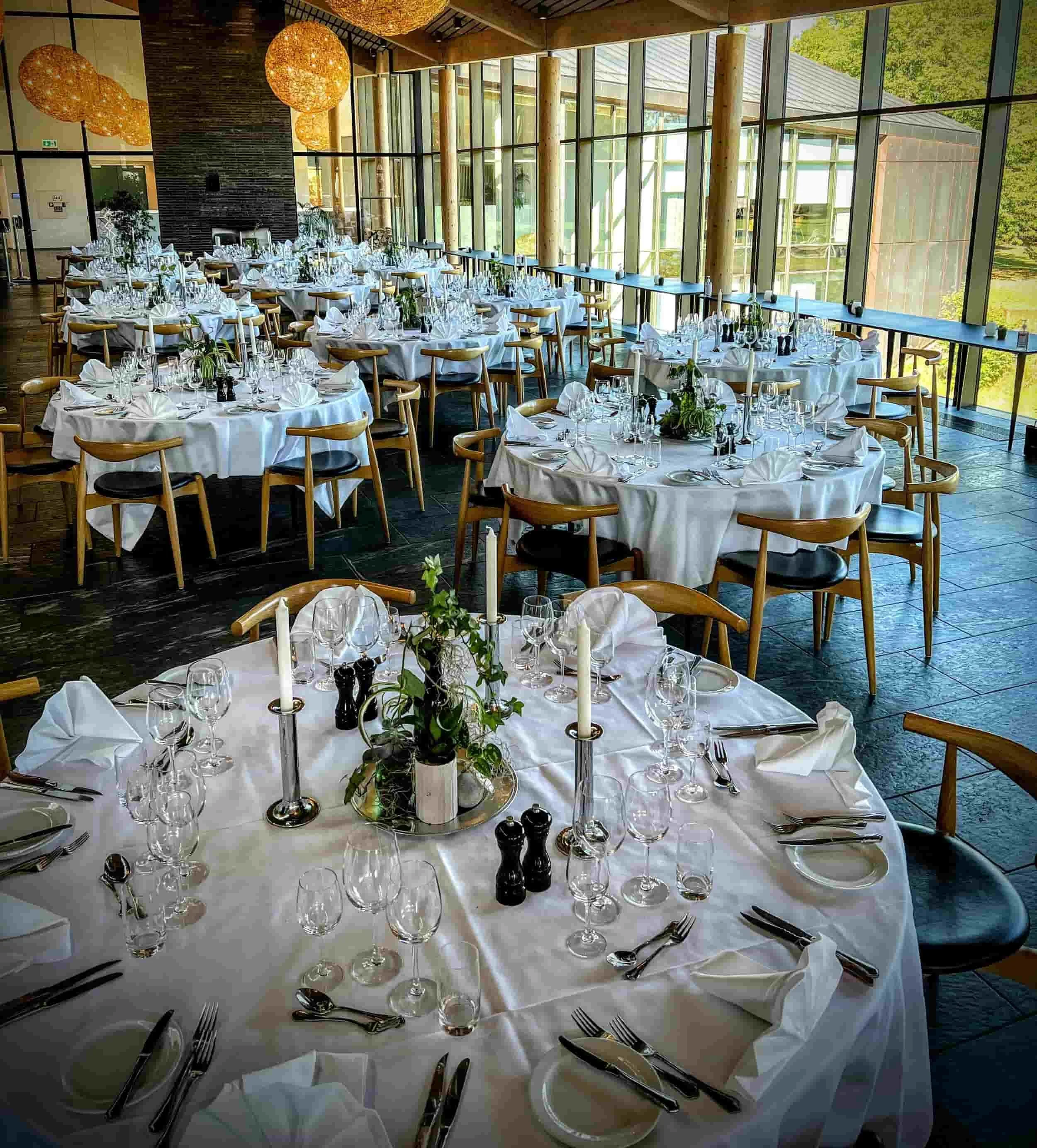 Bæredygtige plantedekorationer på runde borde i Glostrup Park Hotels restaurant, skabt af VOKS med genbrugsmaterialer og økologiske planter.