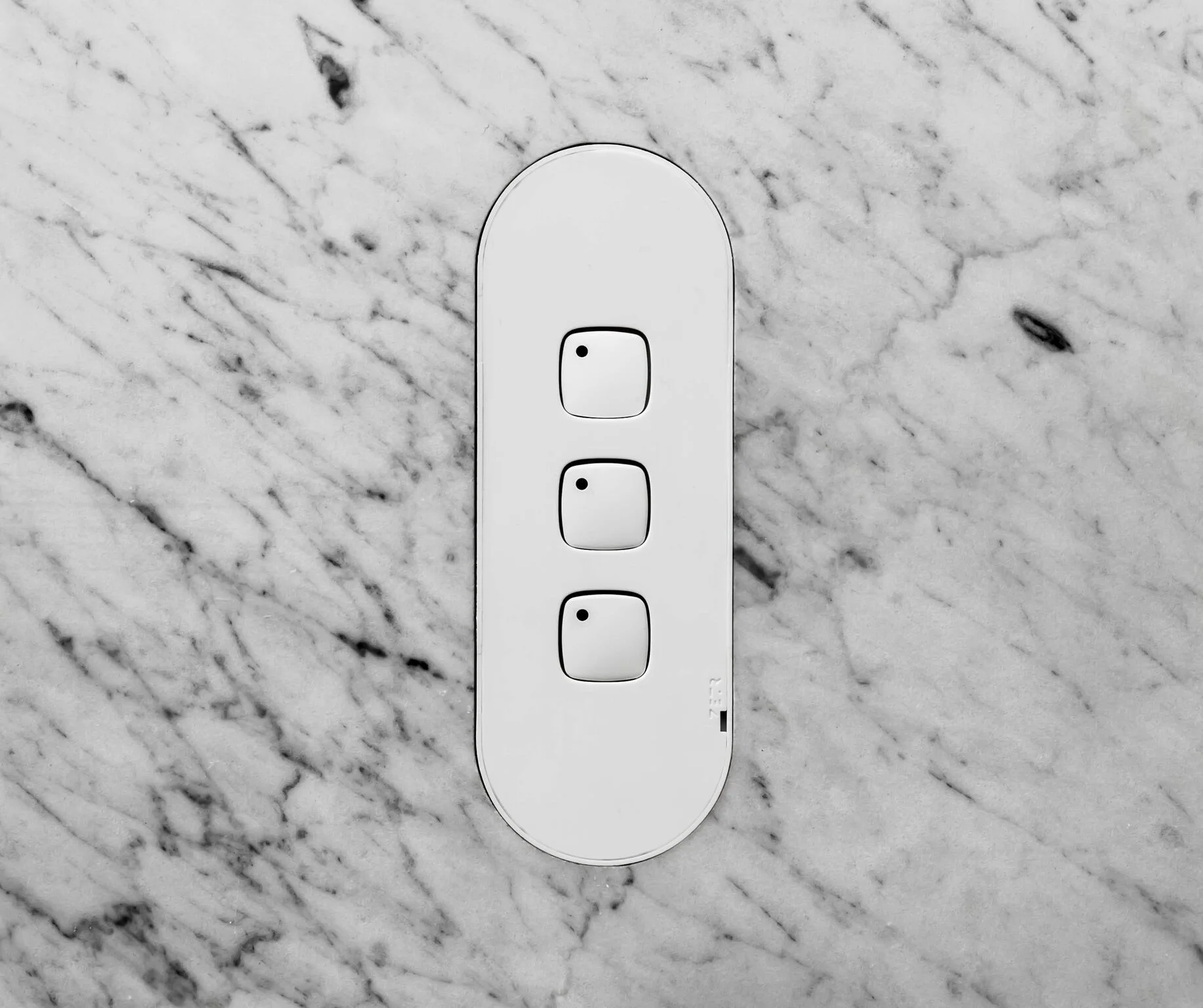 The ZETR 13 three gang switch in mate white with adjustable mounting assembly installed into water jet cut marble.