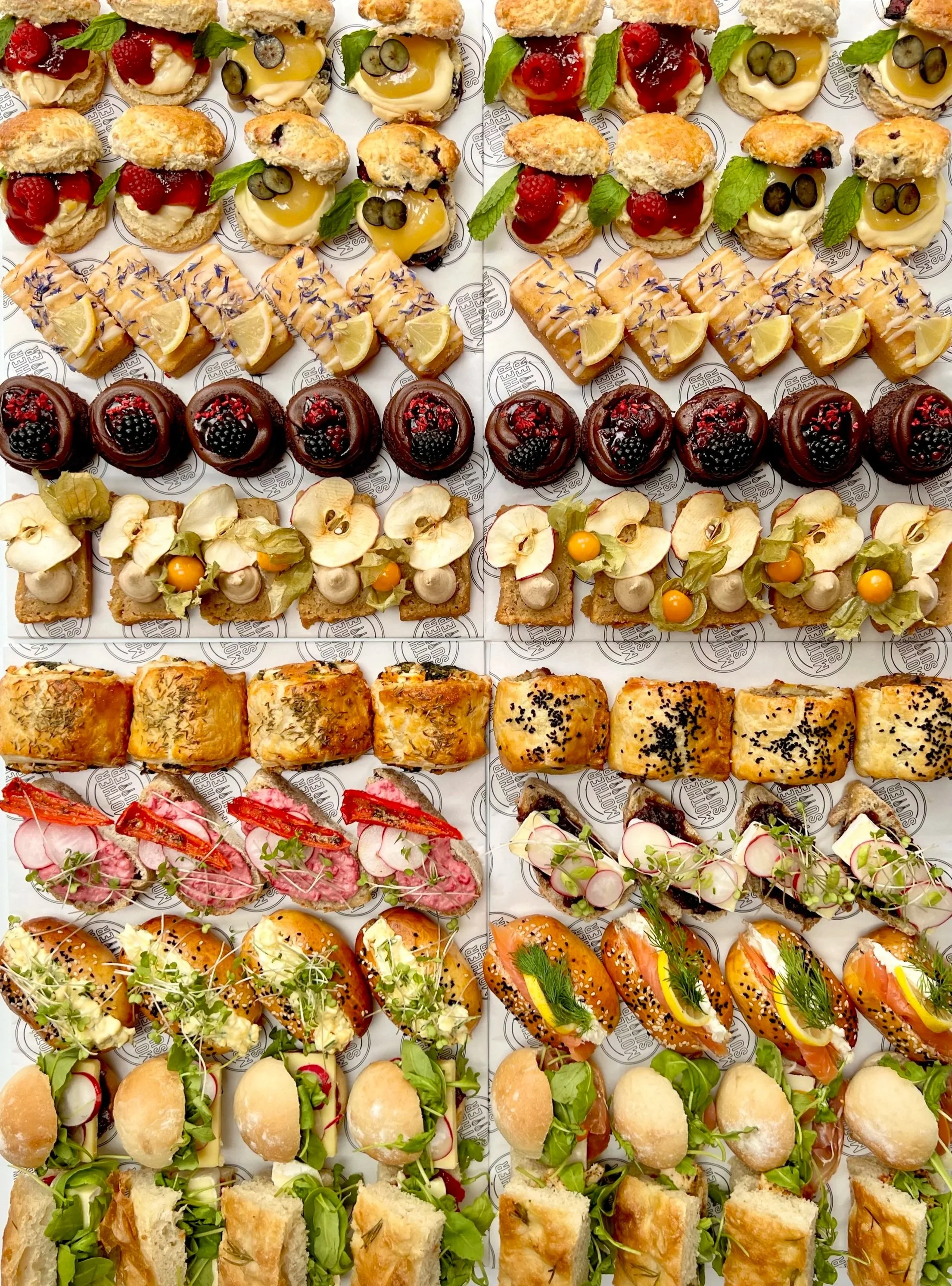 ASSORTED SANDWICHES, PASTRIES, CAKES & SCONES ARRANGED BEAUTIFULLY FOR AFTERNOON TEA EVENT CATERING.