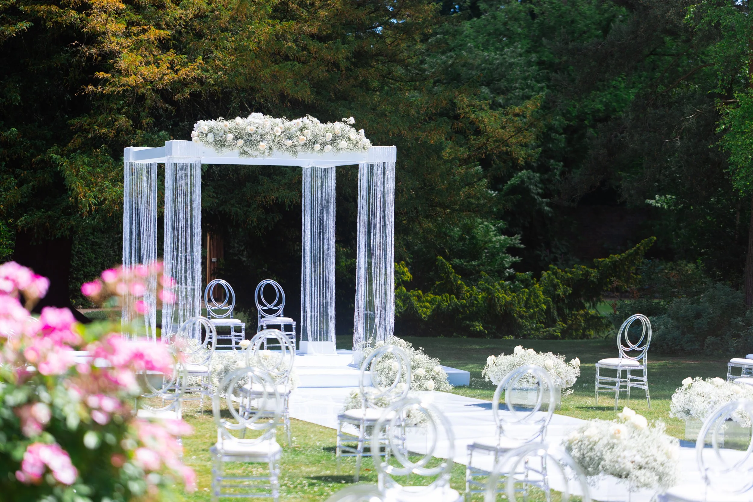 White floral arch framing an outdoor wedding ceremony
