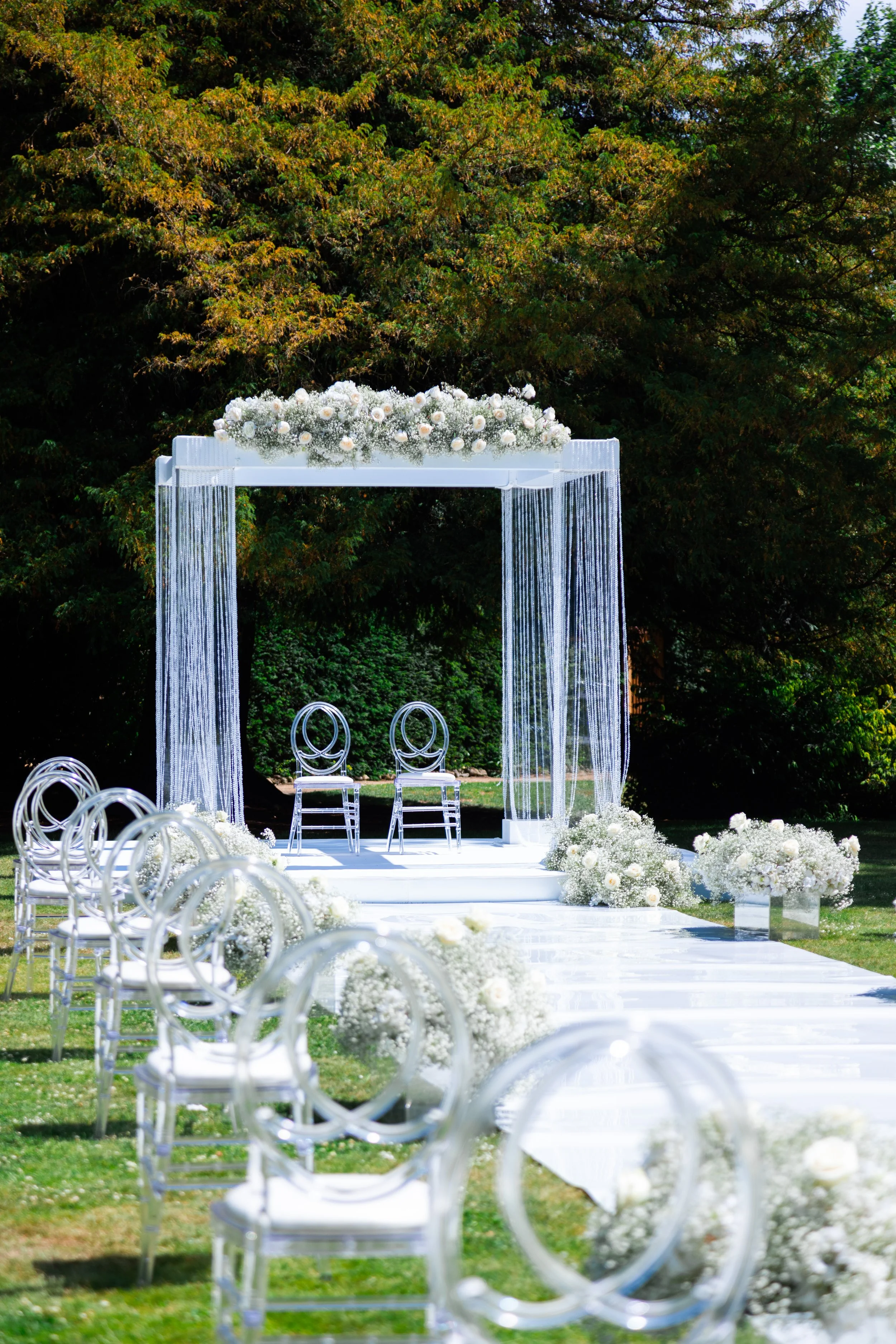 White floral arrangements lining an outdoor wedding ceremony aisle
