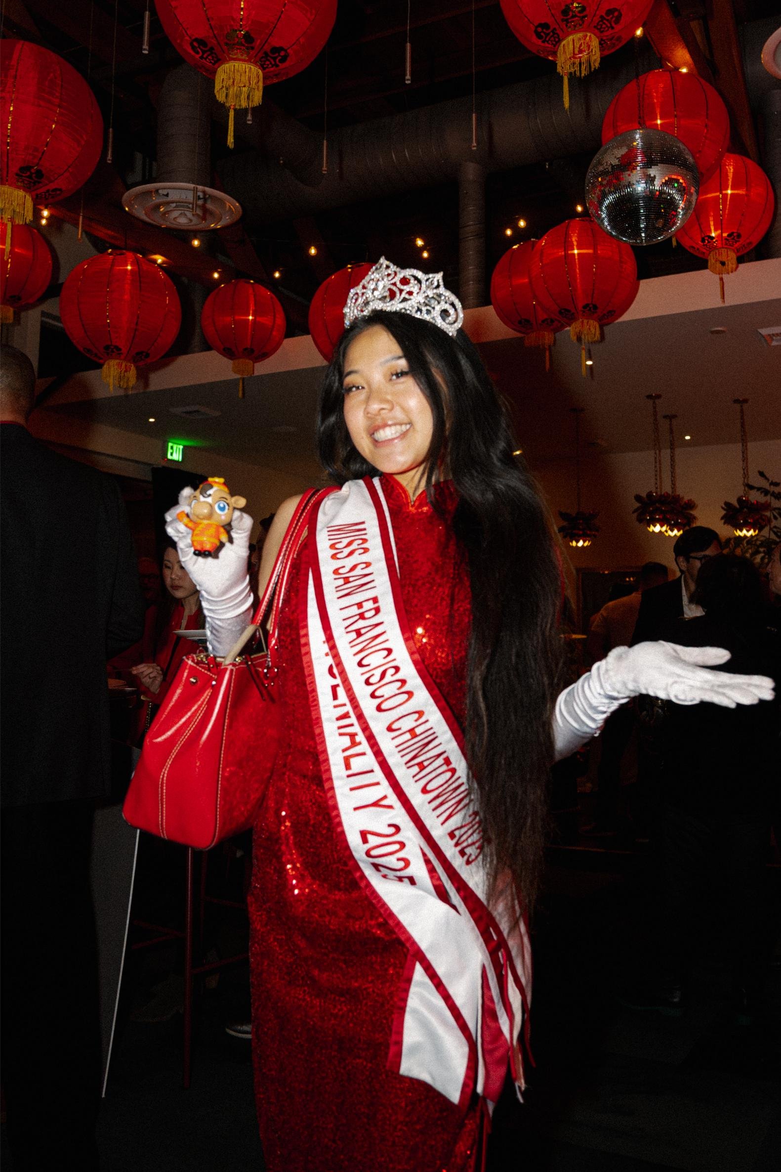 Miss San Francisco Chinatown 2023 celebrating with a crown and sash in a festive event decorated with red lanterns and a disco ball.