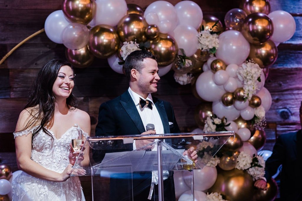 Bride and groom speech in front of balloon arch