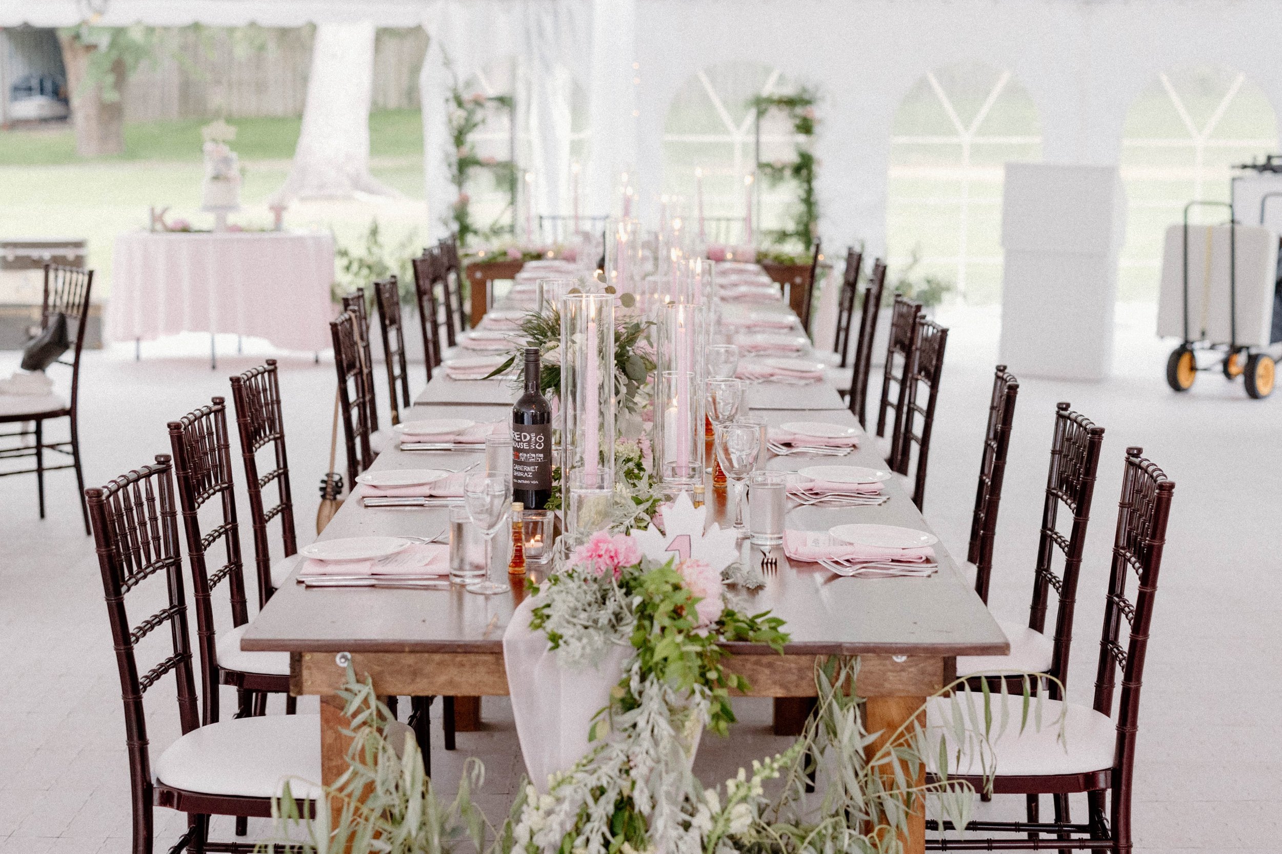 Long wood tables with wood chairs in tented wedding reception